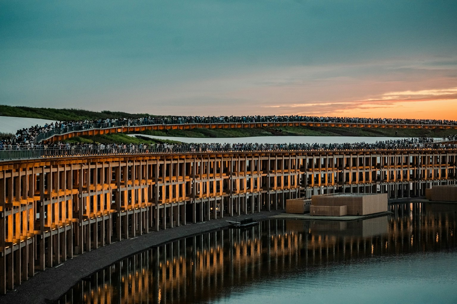 美しい夕焼けの中で反射する水面と曲線状の桟橋が特徴の風景