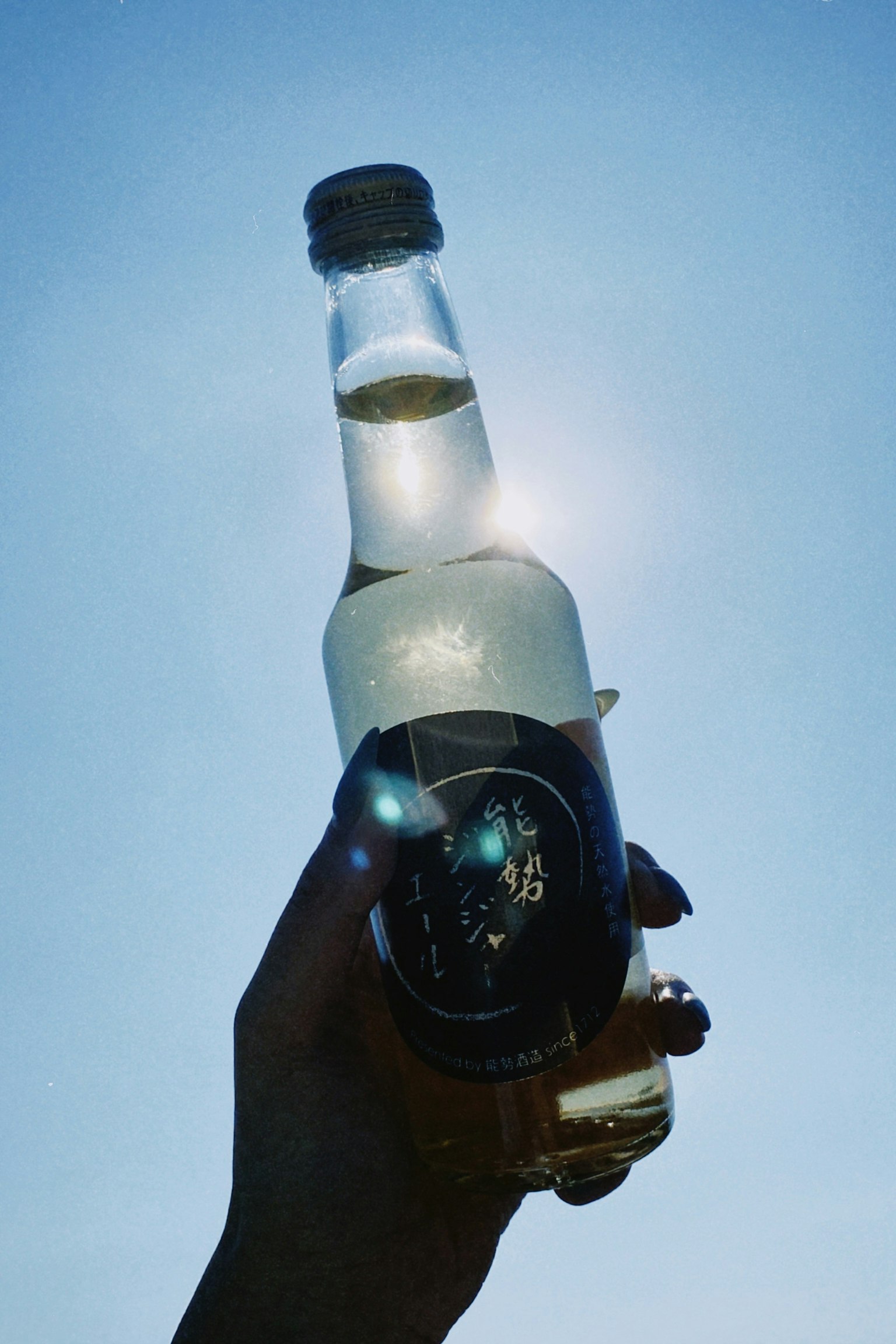 Silhouette minuman botol yang dipegang di bawah langit biru