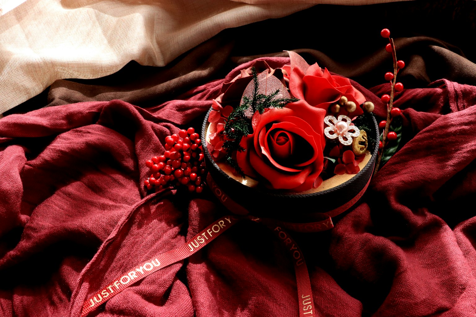 Eine Schüssel mit roten Rosen und dekorativen Elementen auf tiefrotem Stoff