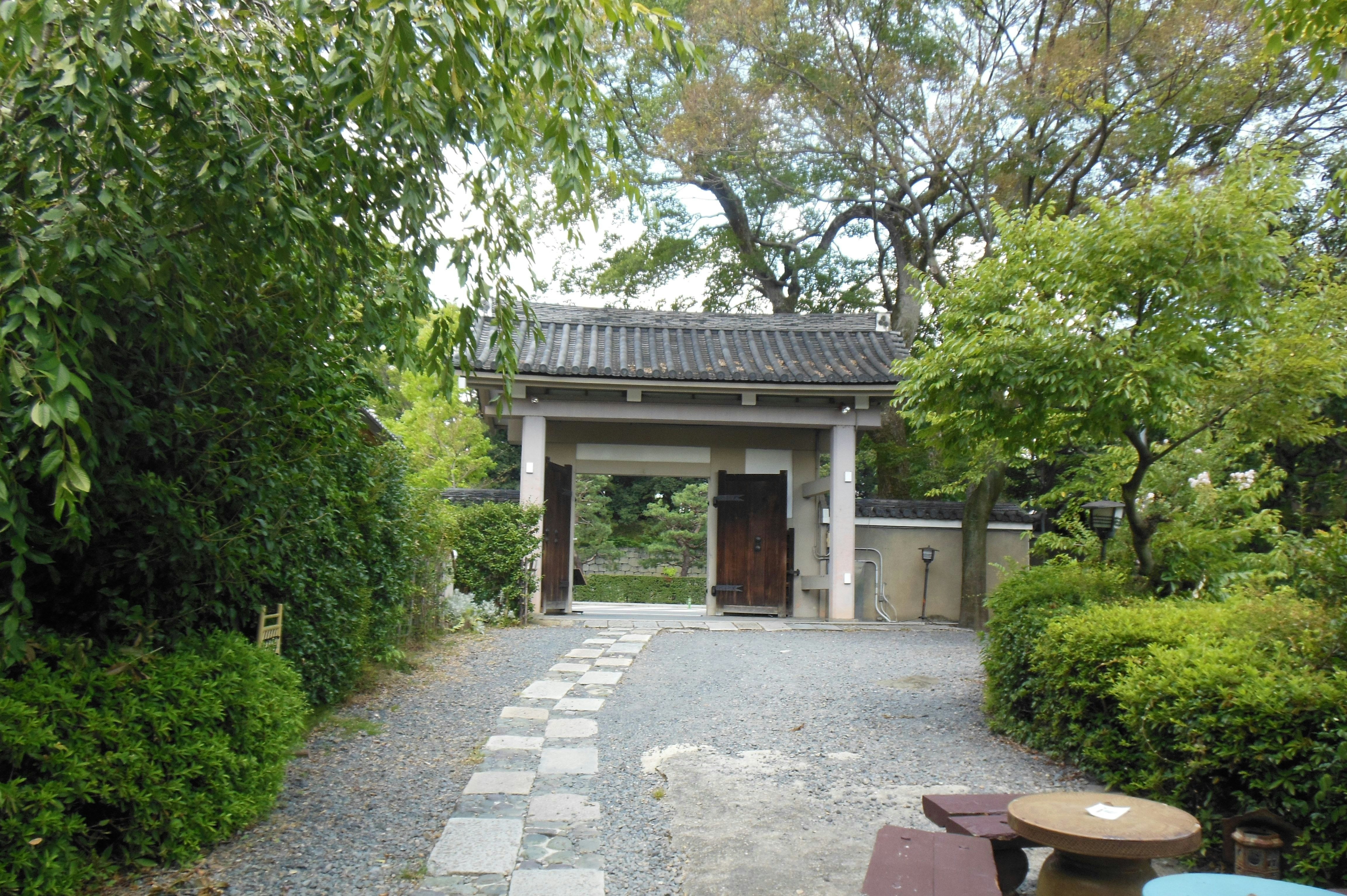 緑に囲まれた和風の庭園入口の門と小道