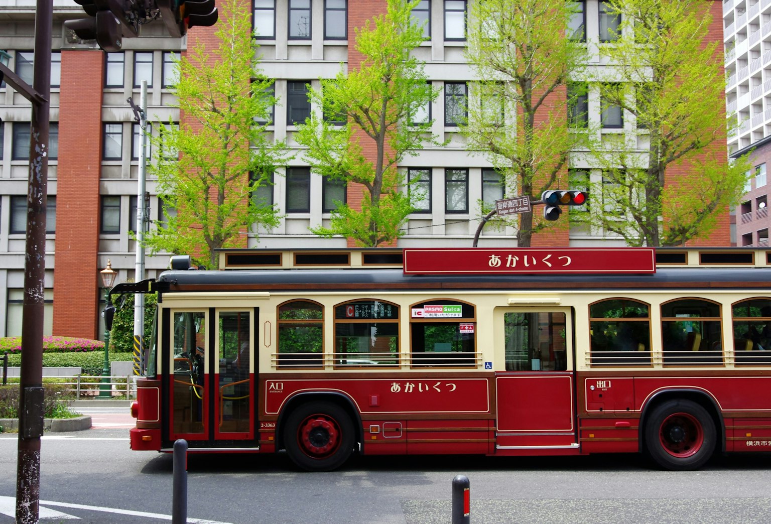 Un autobus retro rosso che passa davanti ad alberi verdi