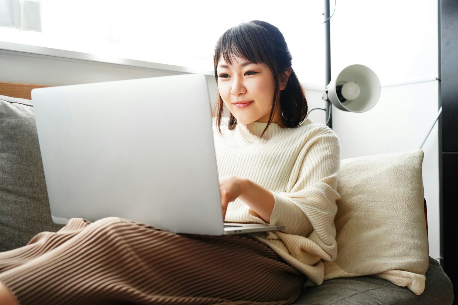 Woman using a laptop while sitting on a sofa