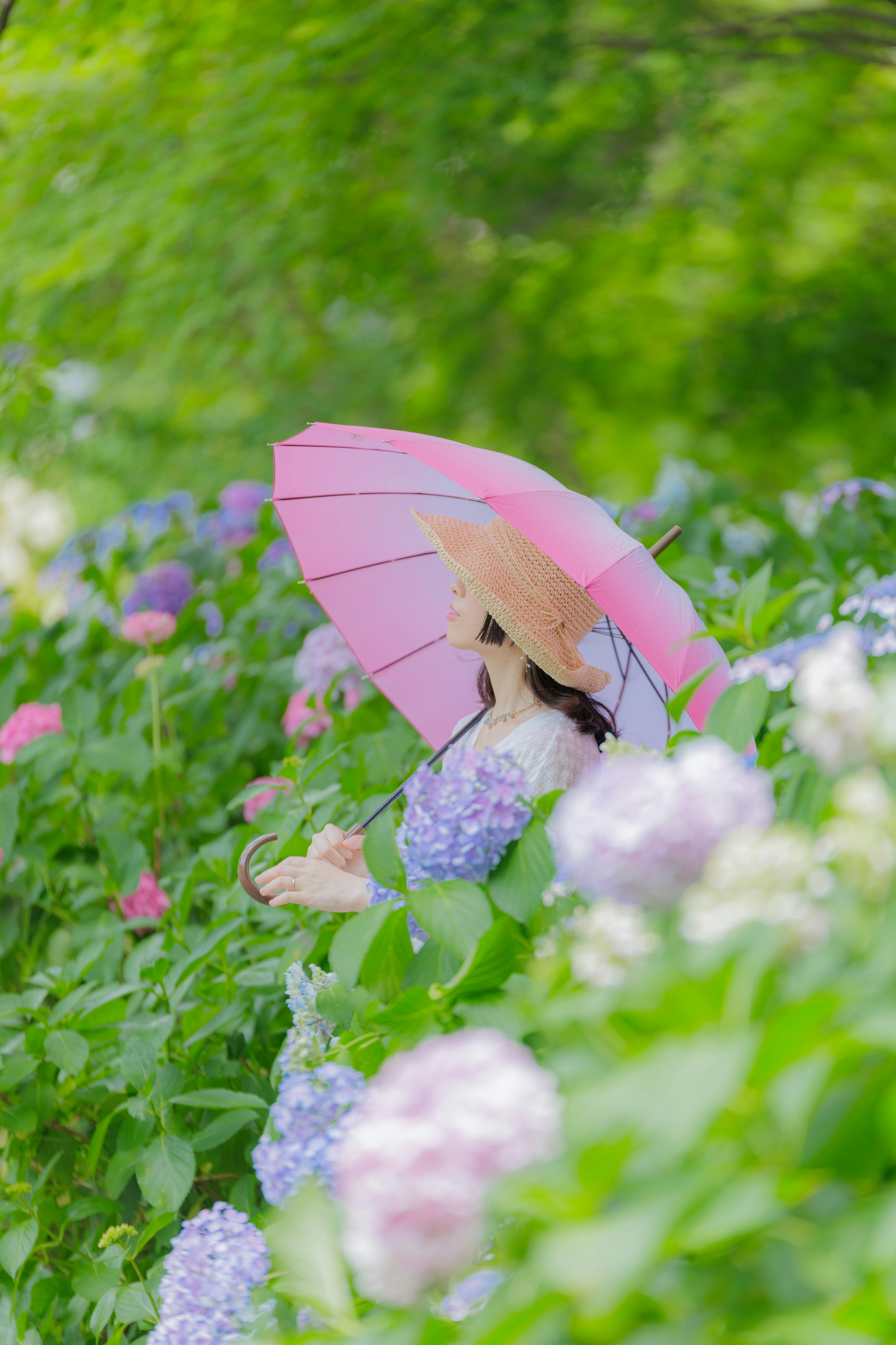 花海里撑着粉色雨伞的女性