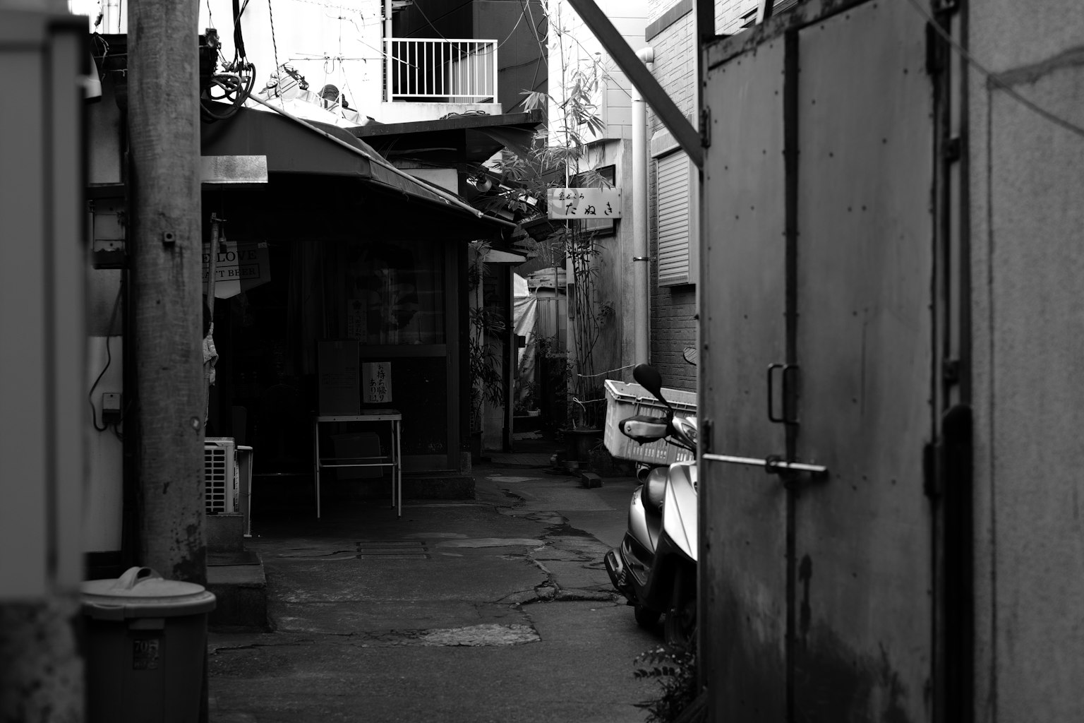 Callejón estrecho con edificios y una silla en un entorno monocromático