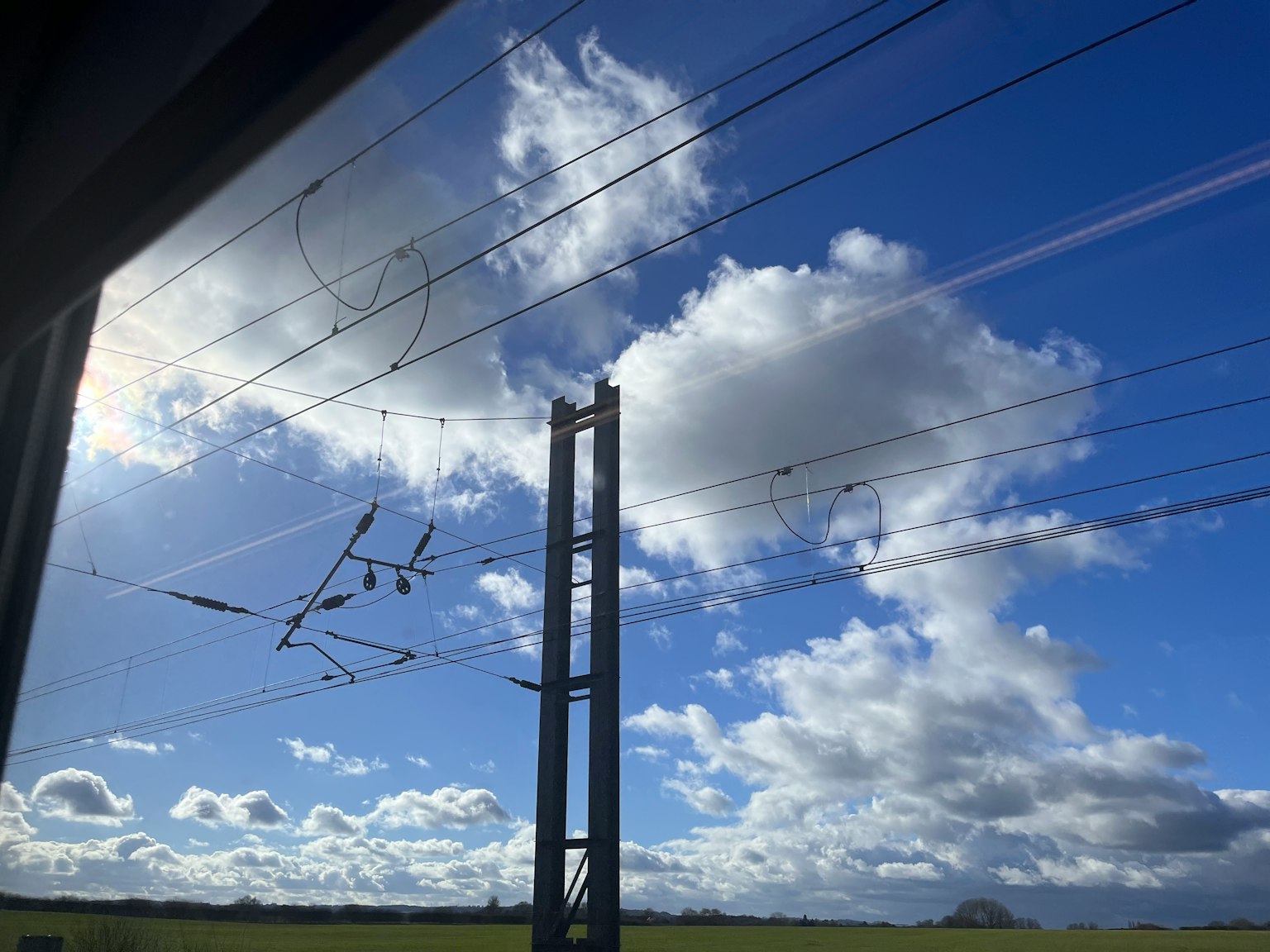 Paisaje con cielo azul nubes blancas y líneas eléctricas ferroviarias