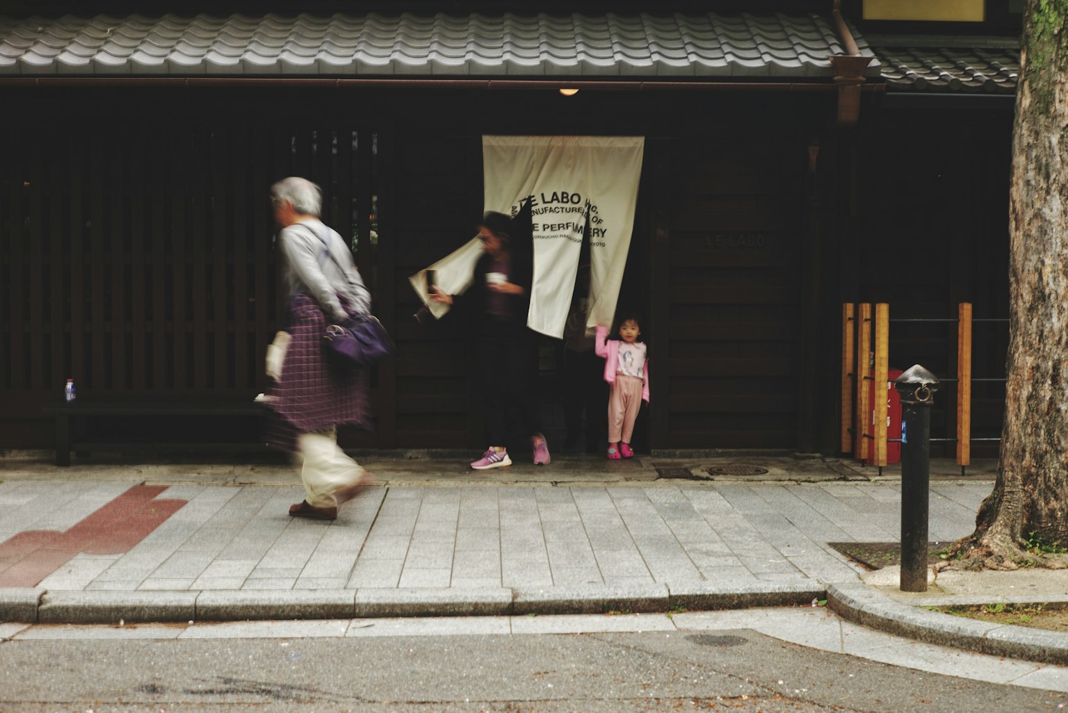 传统日本建筑外观，有人走过和一位小女孩站在附近