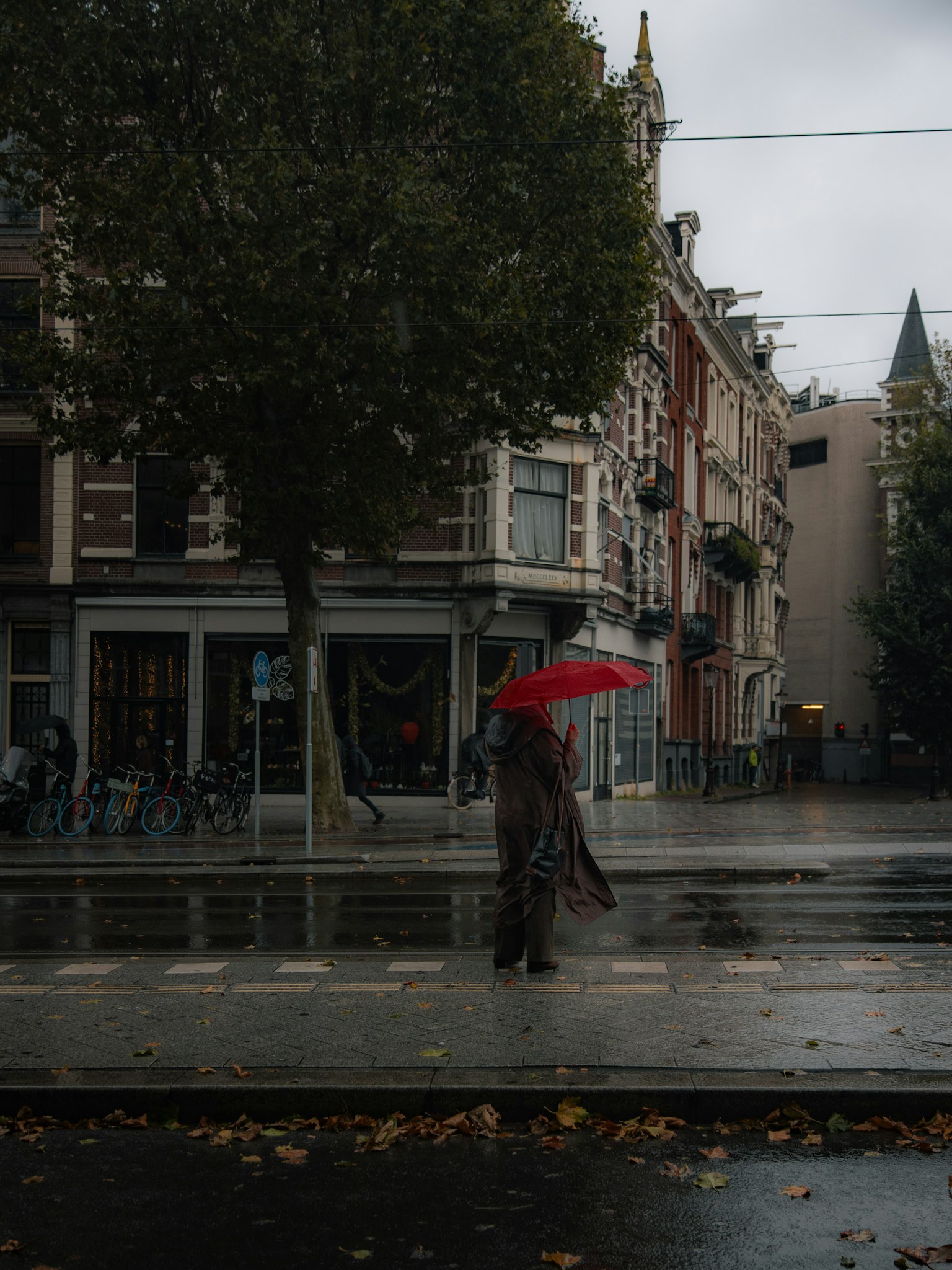 一個人在城市環境中拿著紅傘走在雨中