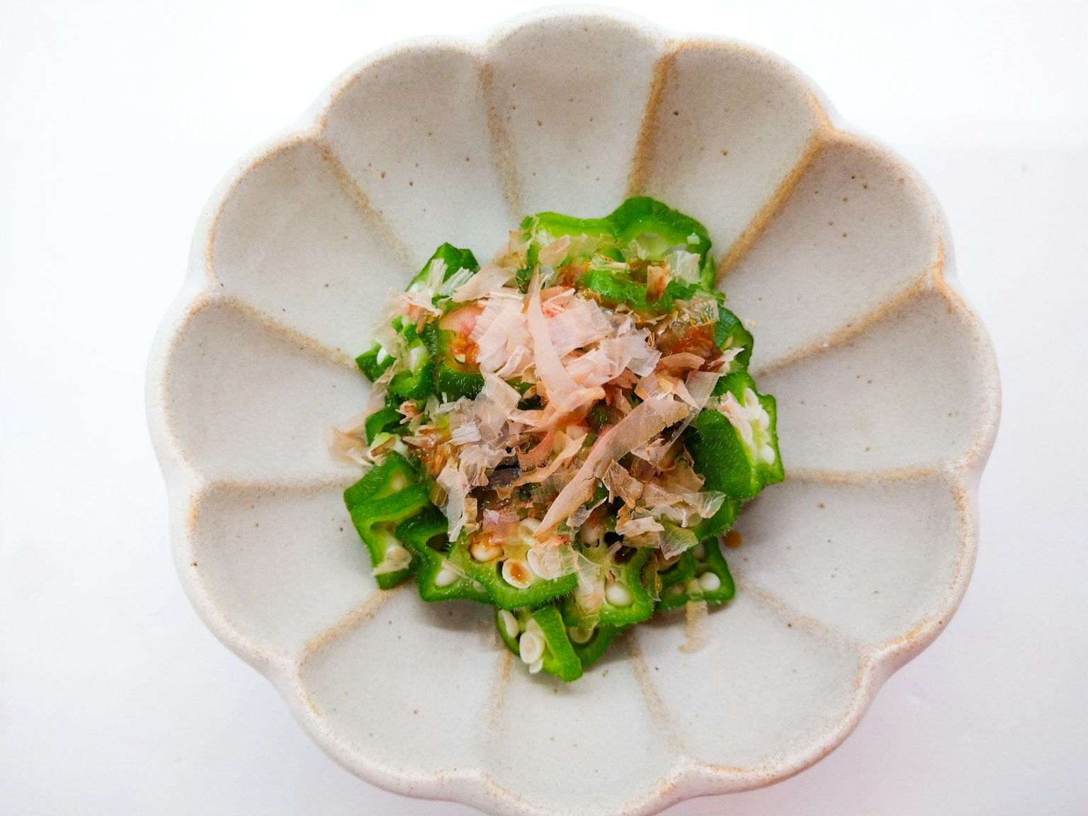 Insalata di verdure verdi e pesce servita in un piatto bianco a forma di fiore