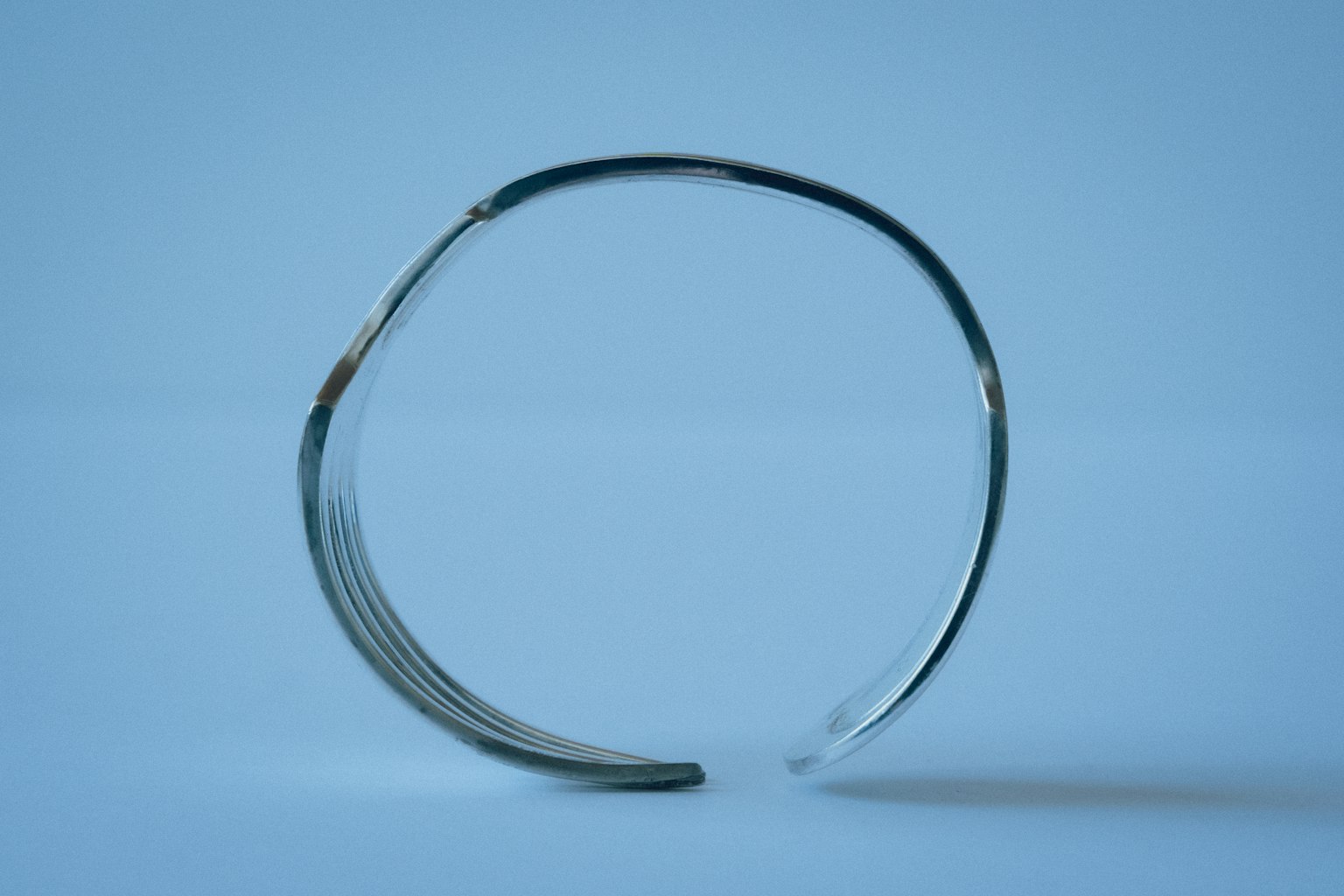 Un bracciale d'argento semplice posato su uno sfondo blu