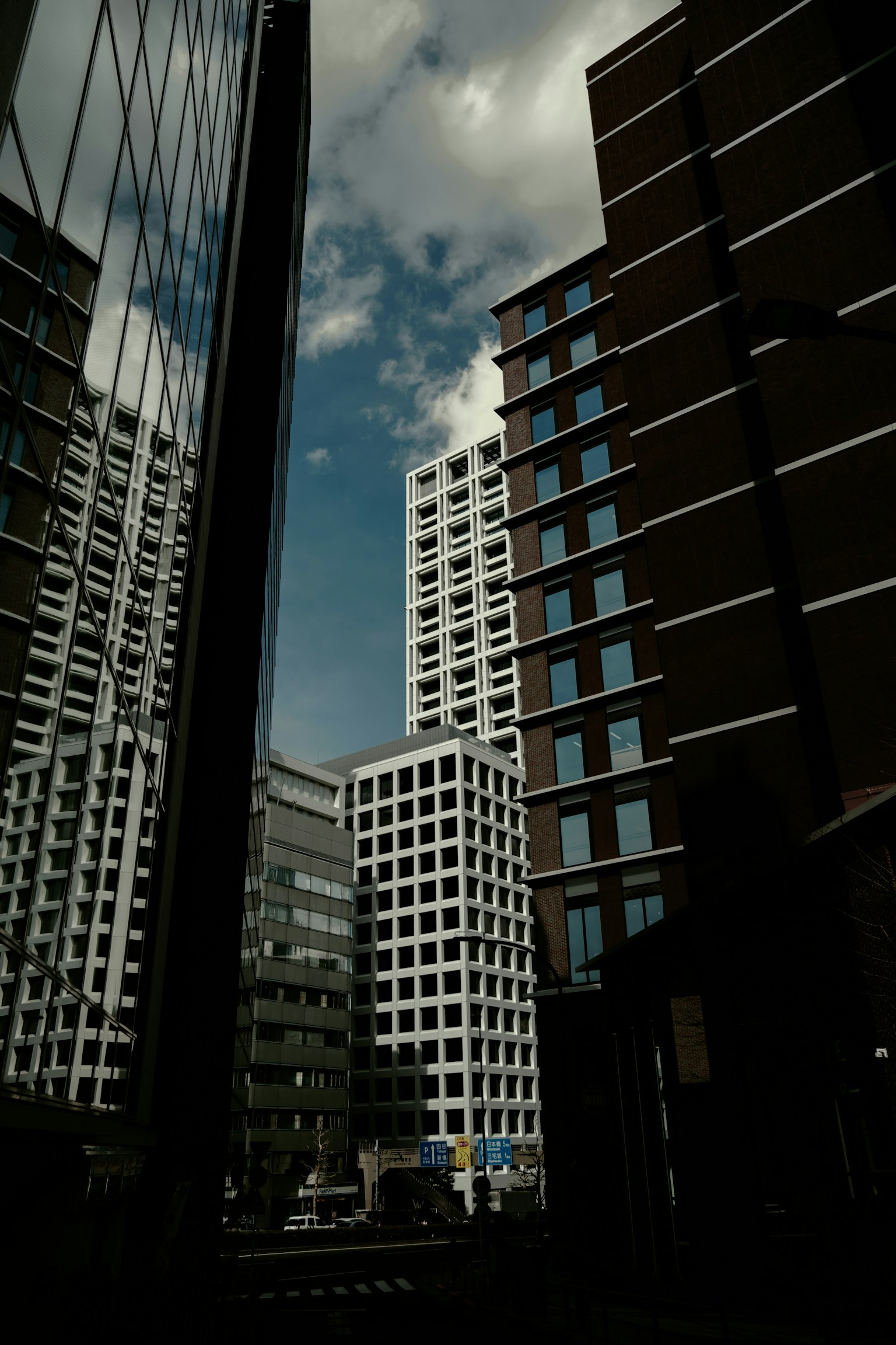 Pemandangan perkotaan dengan gedung pencakar langit yang memantulkan langit biru dan awan