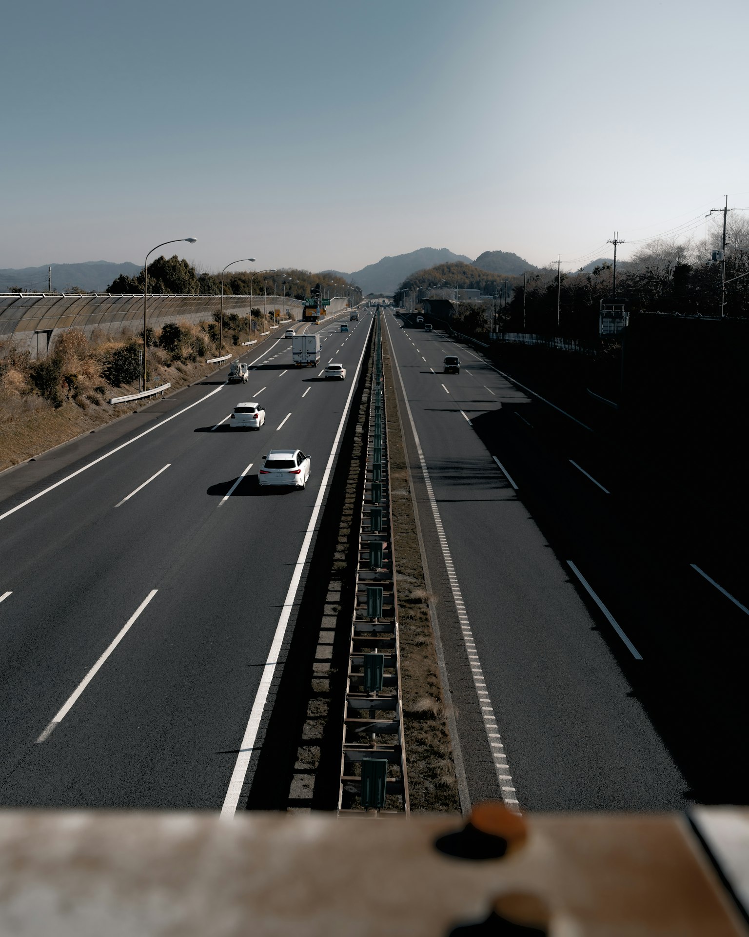 Vista desde arriba de la carretera mostrando coches circulando con montañas al fondo