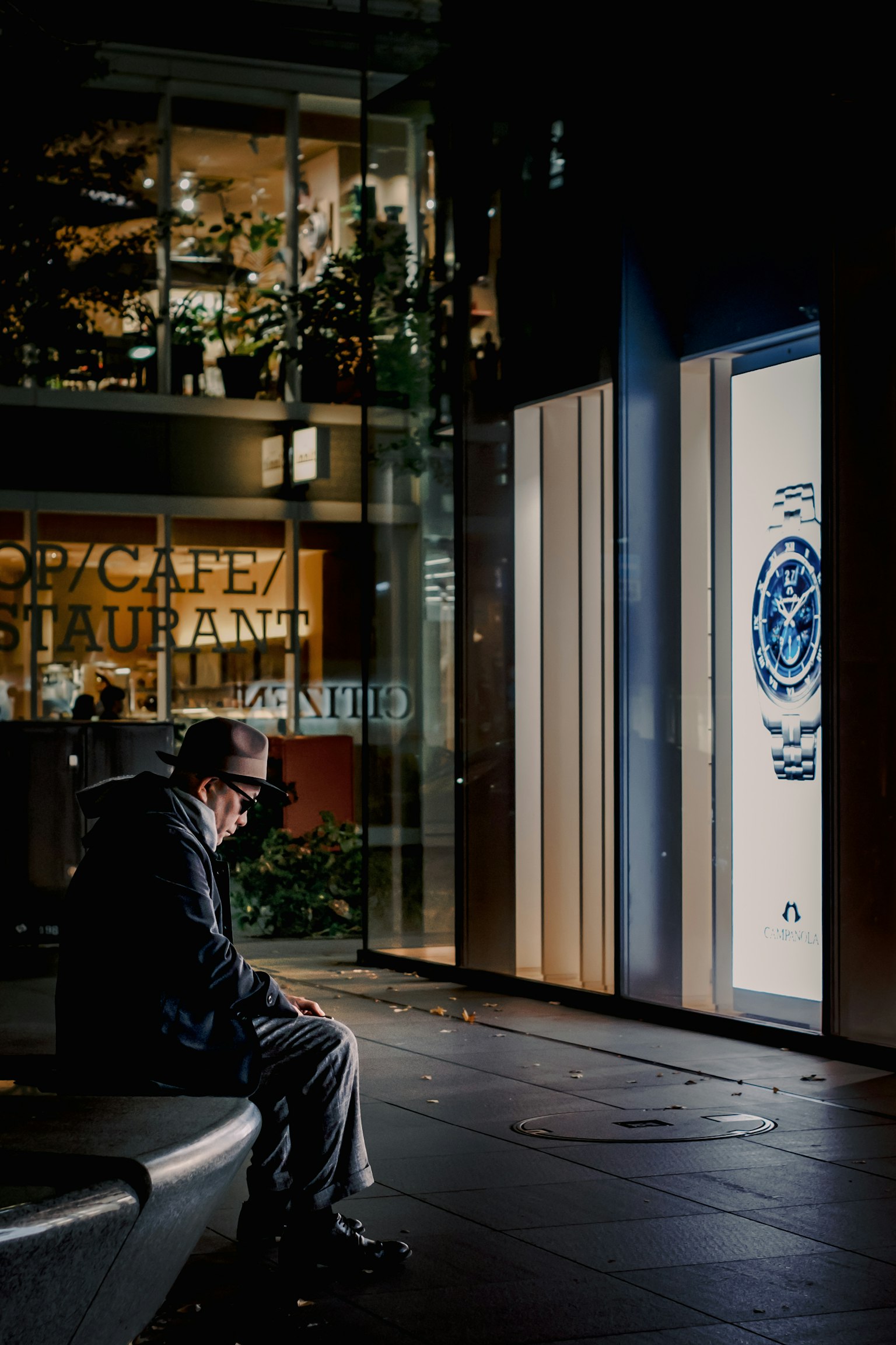 A man deep in thought at night near a bright sign
