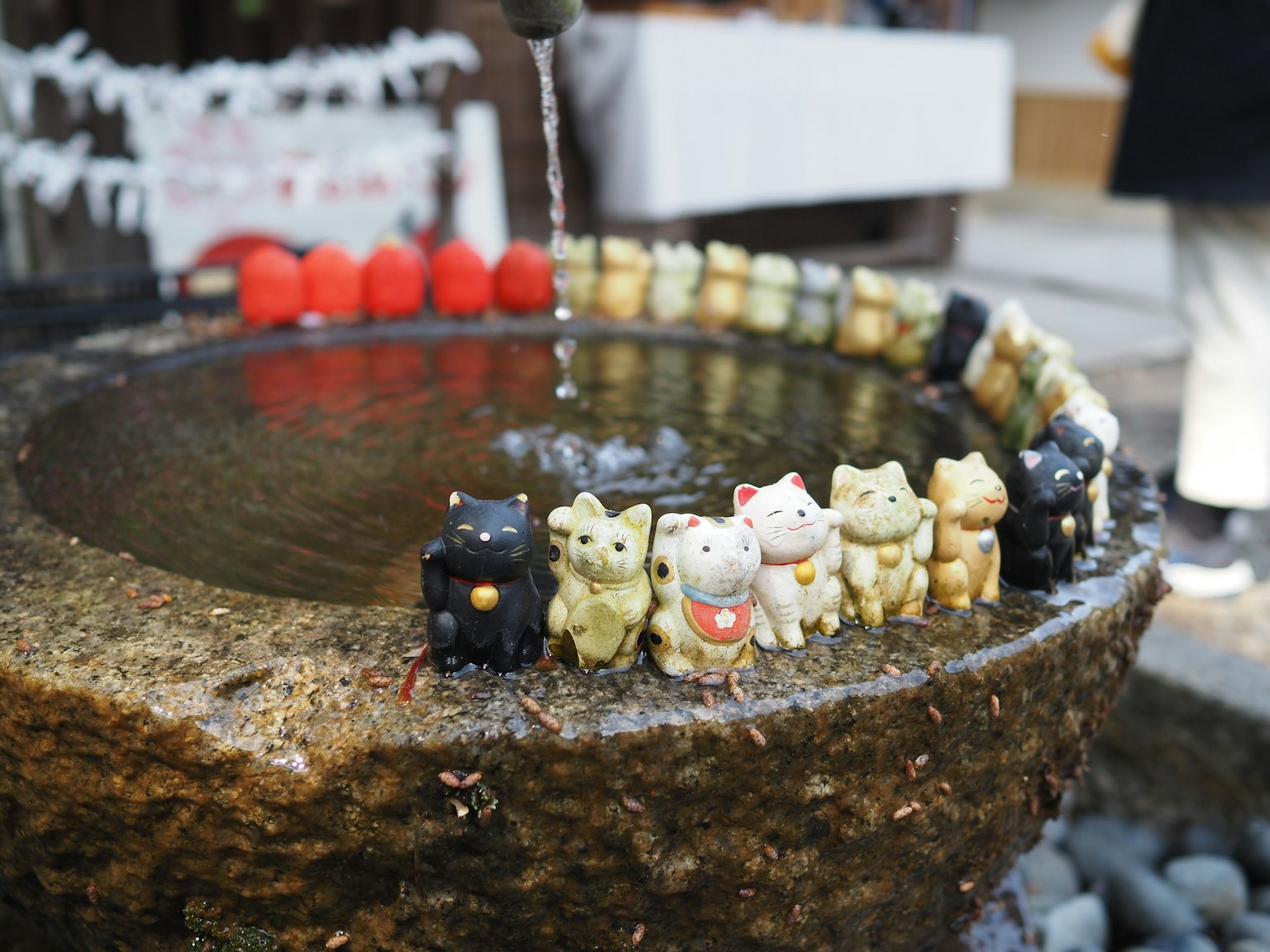 Un lavabo de piedra con adorables figuras de gatos dispuestas alrededor del agua