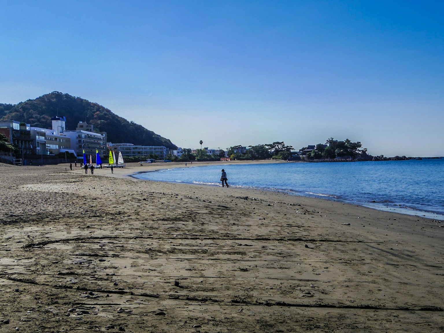 Scena di spiaggia serena con persone che camminano lungo la riva