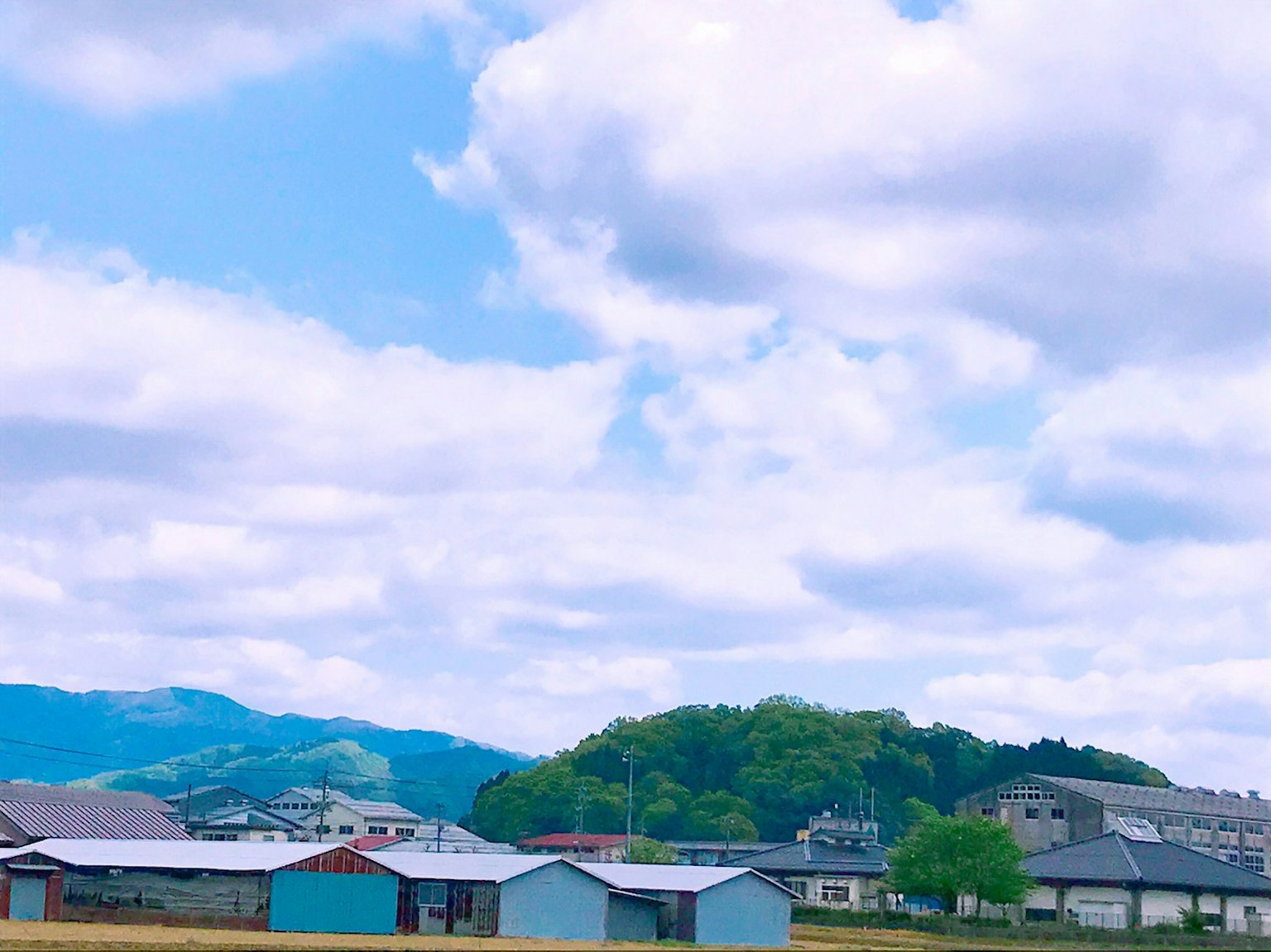 ทิวทัศน์สวยงามที่มีท้องฟ้าสีฟ้าและเมฆขาวโรงเก็บของสีสันสดใสและเนินเขาสีเขียว