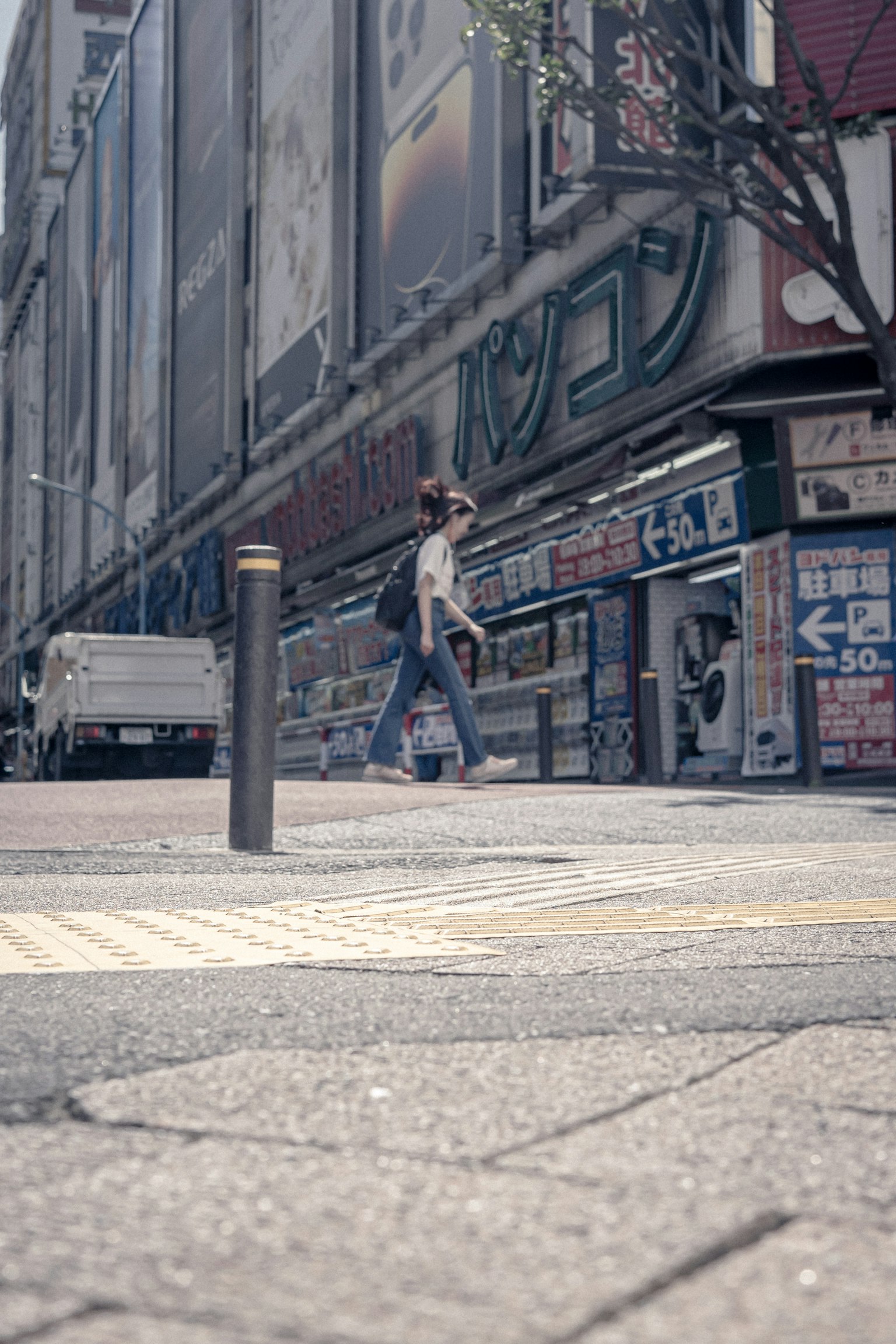 A woman walking on the street with commercial building signs visible