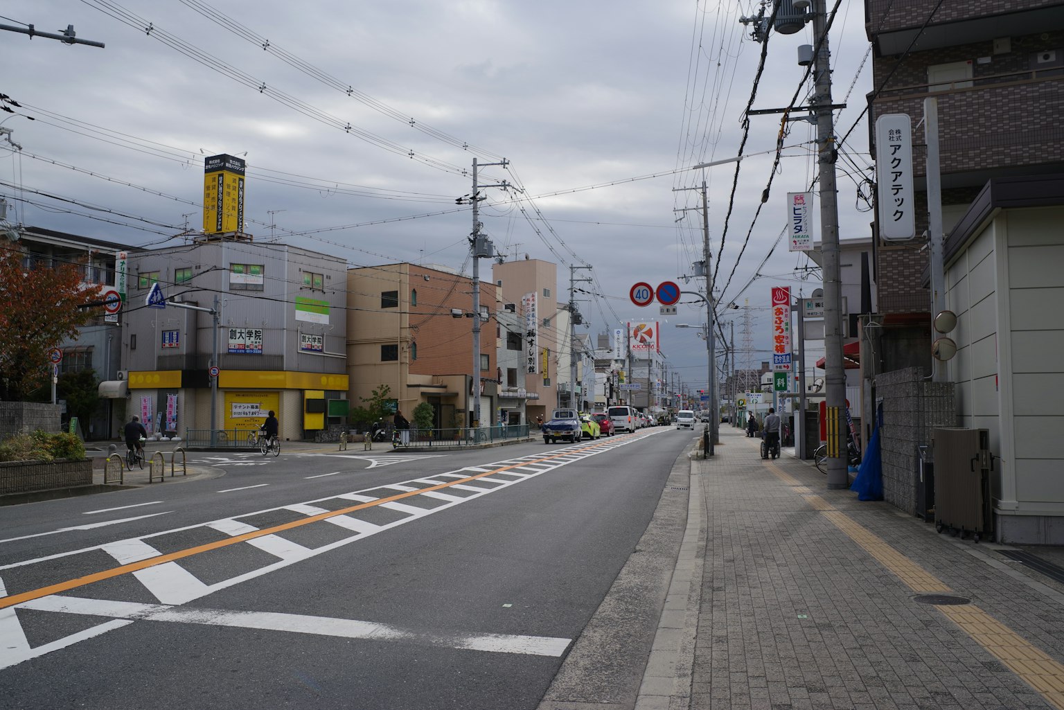 Street view in Japan under cloudy sky featuring commercial buildings and road signs