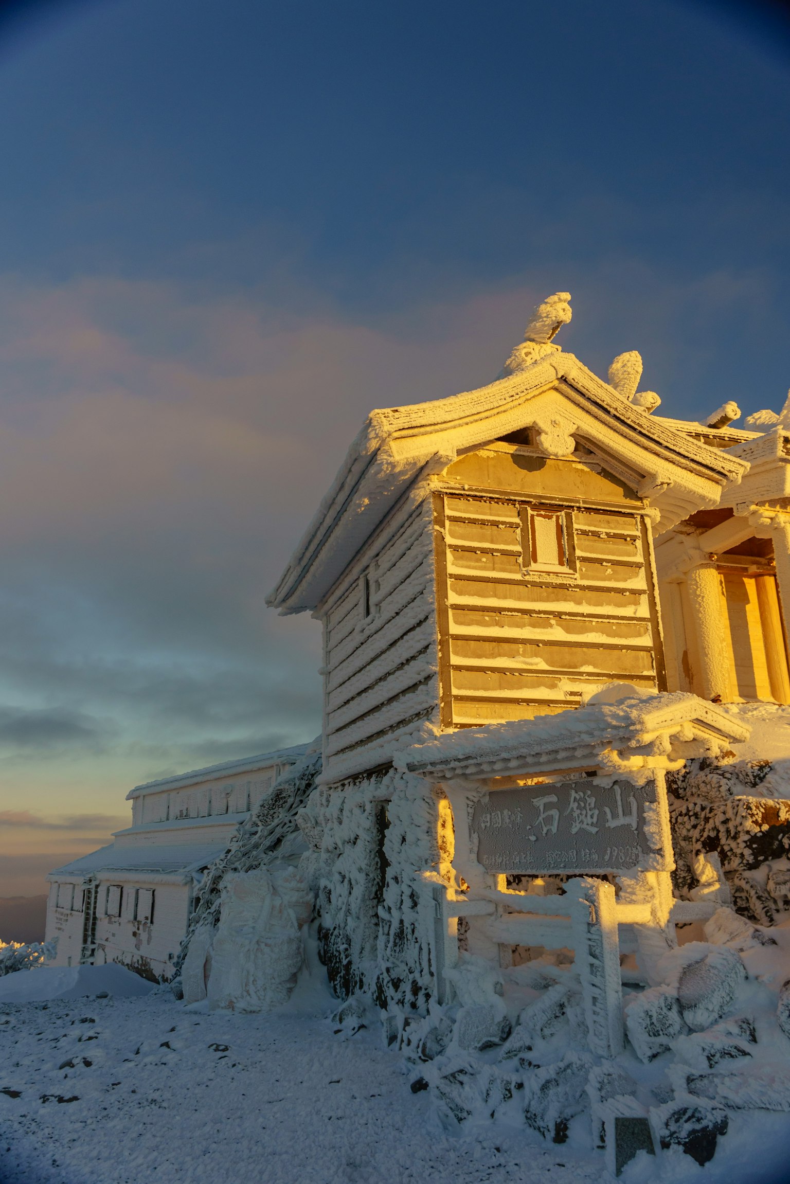 Un edificio di un santuario coperto di neve illuminato dalla luce dorata del tramonto