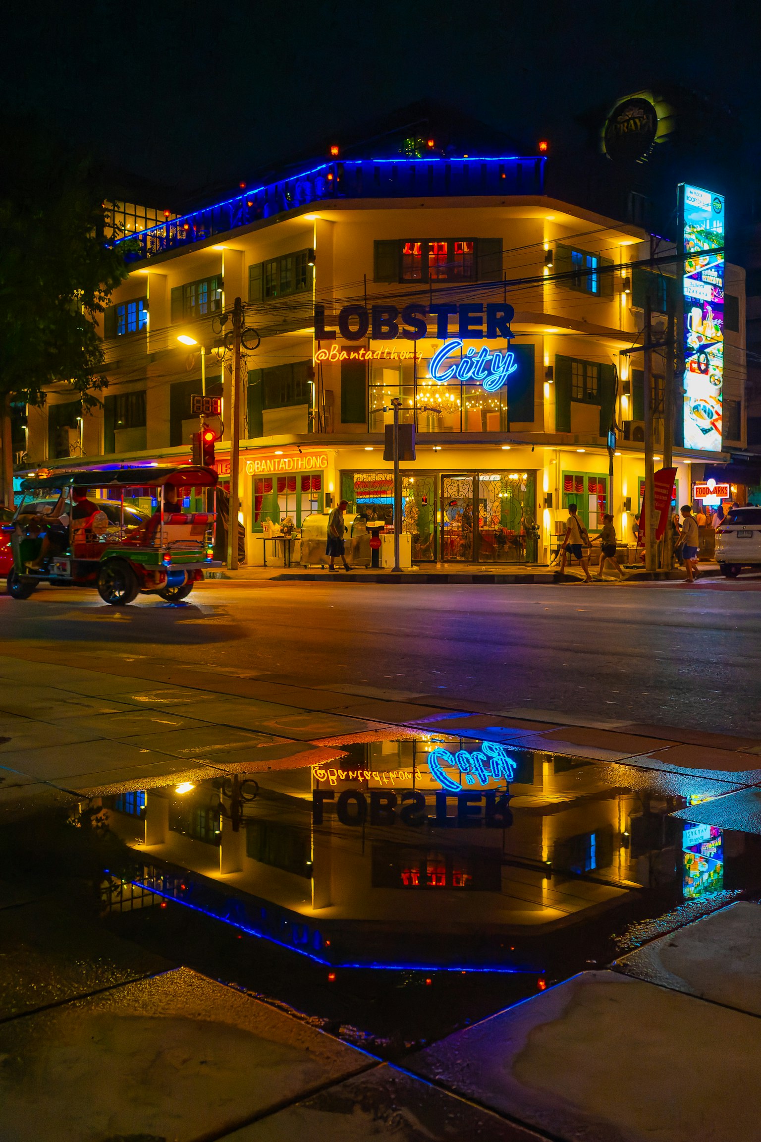 夜間照亮的龍蝦招牌建築映照在水坑中