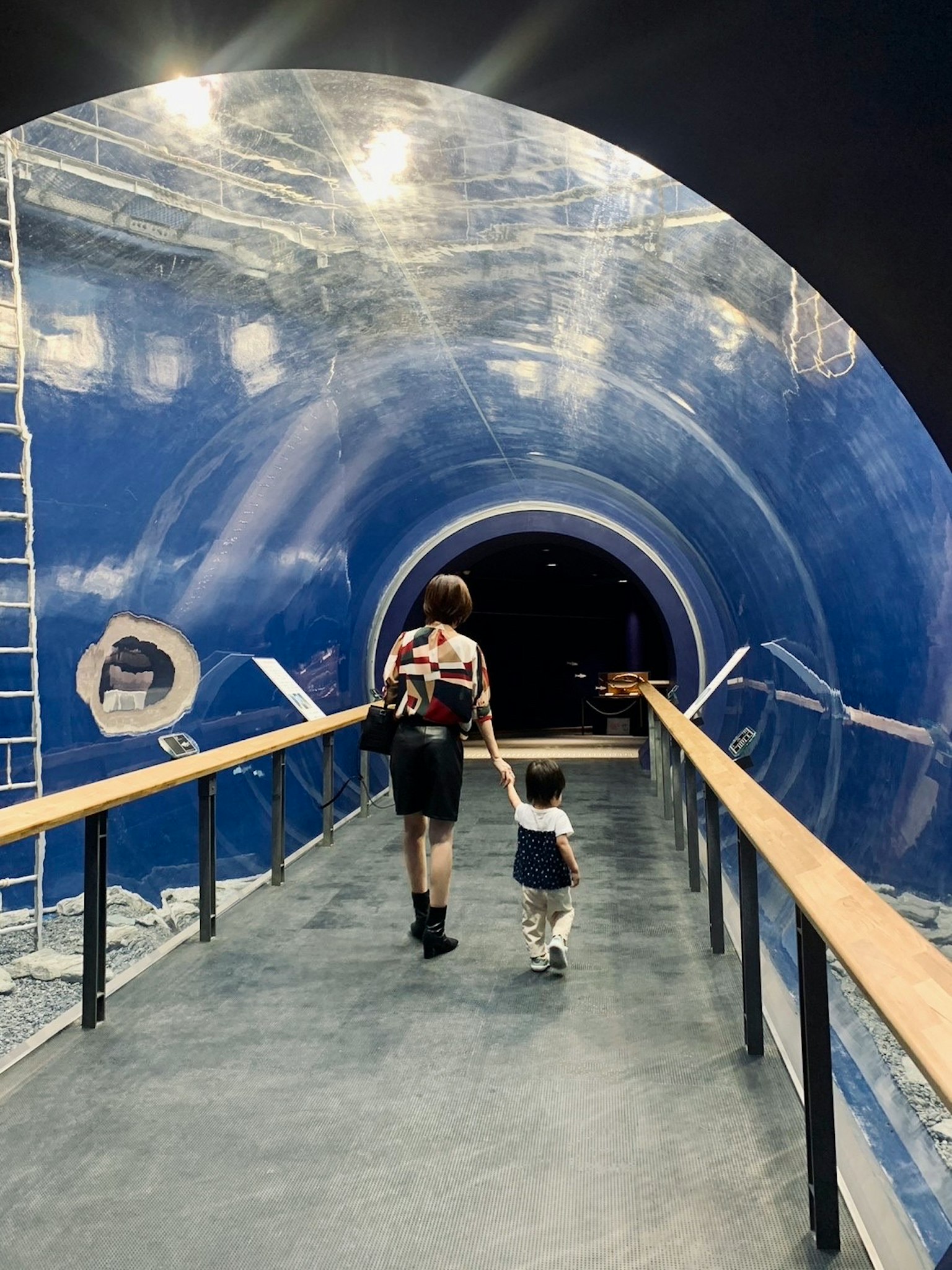 Un parent et un enfant marchant dans un tunnel bleu