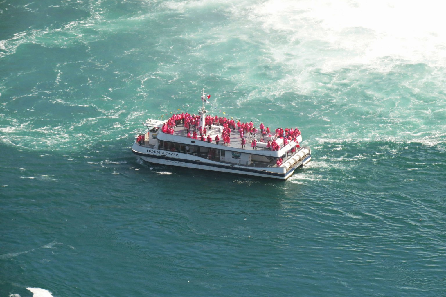 Barca turistica circondata dall'acqua con passeggeri in abbigliamento rosso