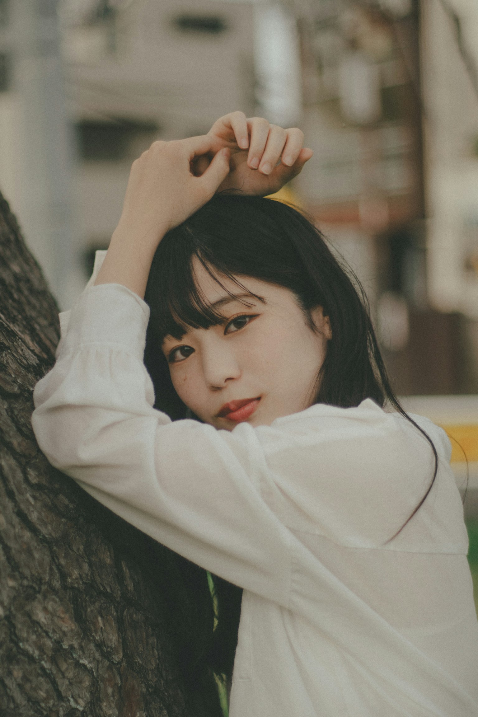 나무에 기대어 흰 셔츠를 입은 여성