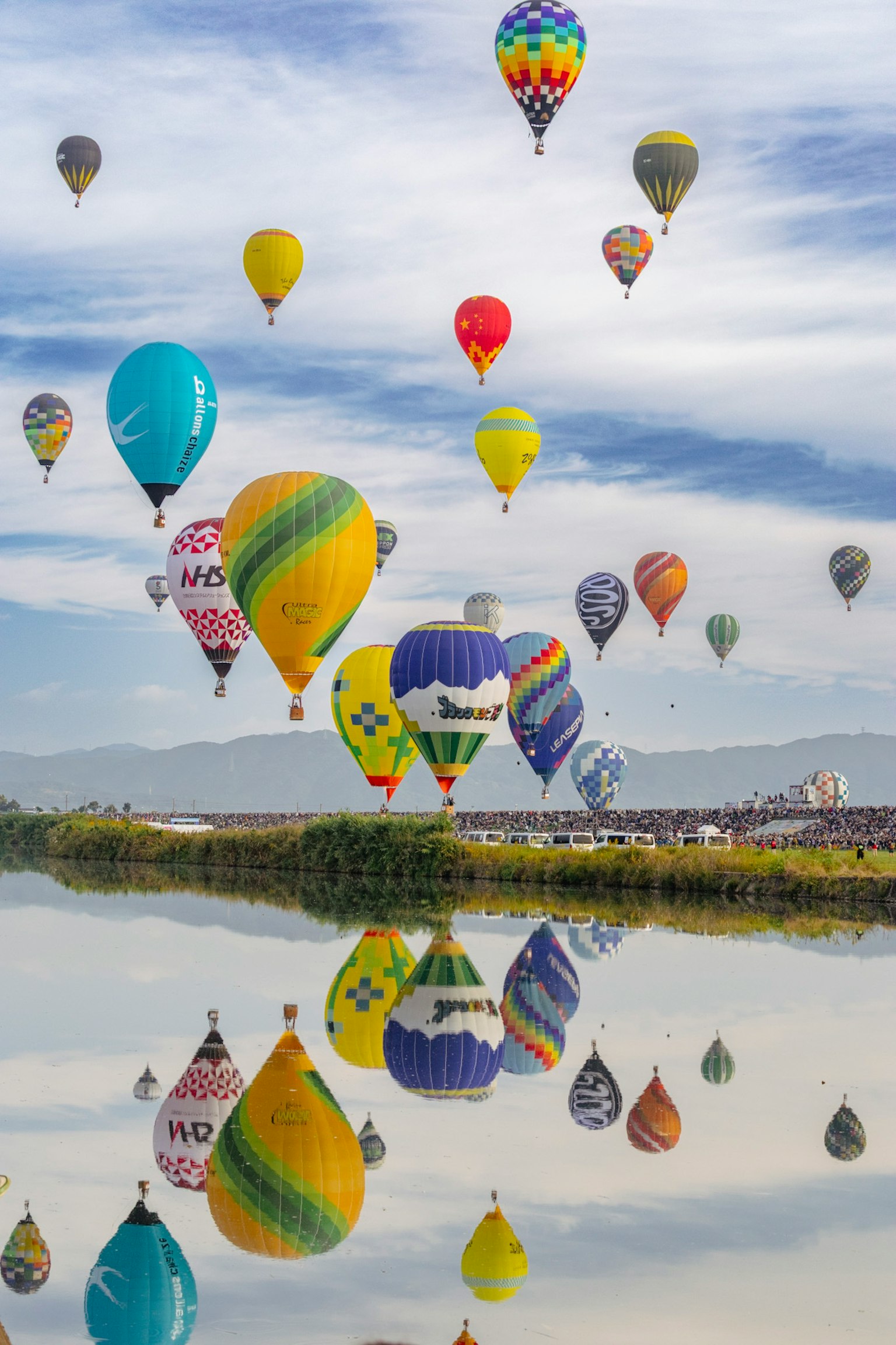 色とりどりの熱気球が空を飛び水面に映る美しい風景