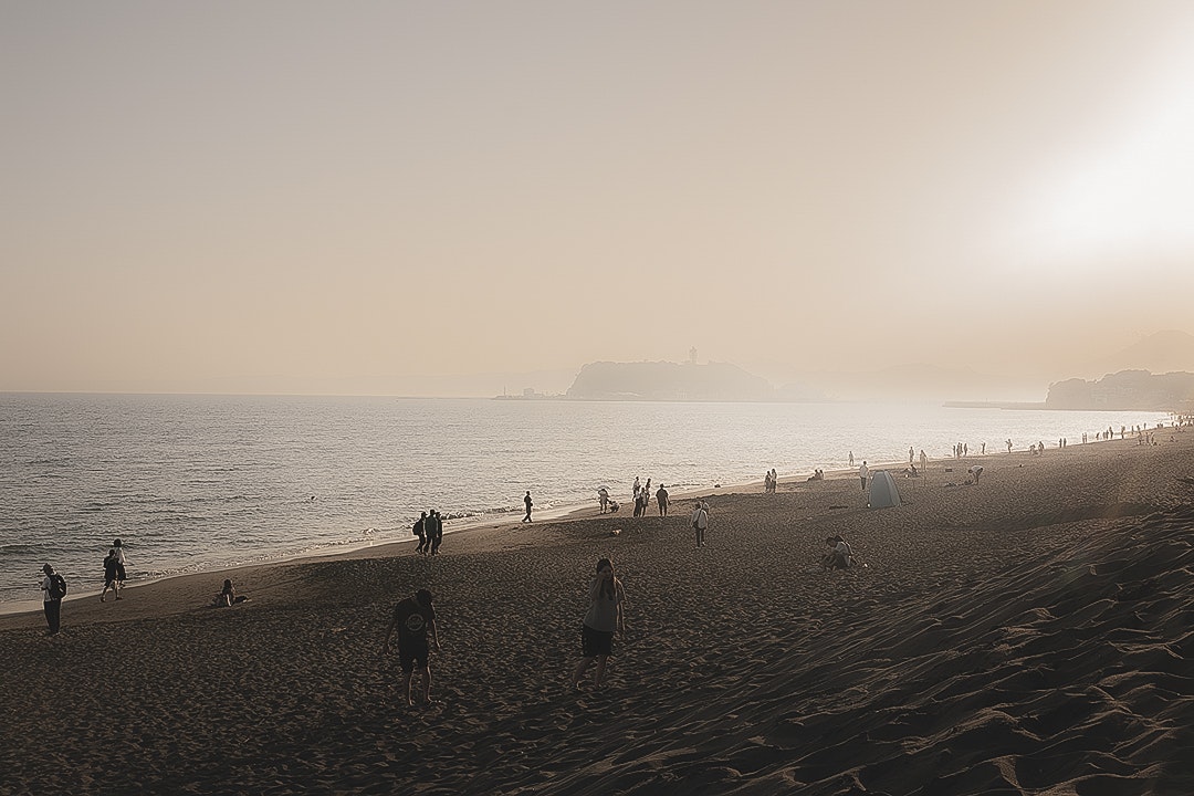 夕暮れの砂浜を歩く人々と海の風景