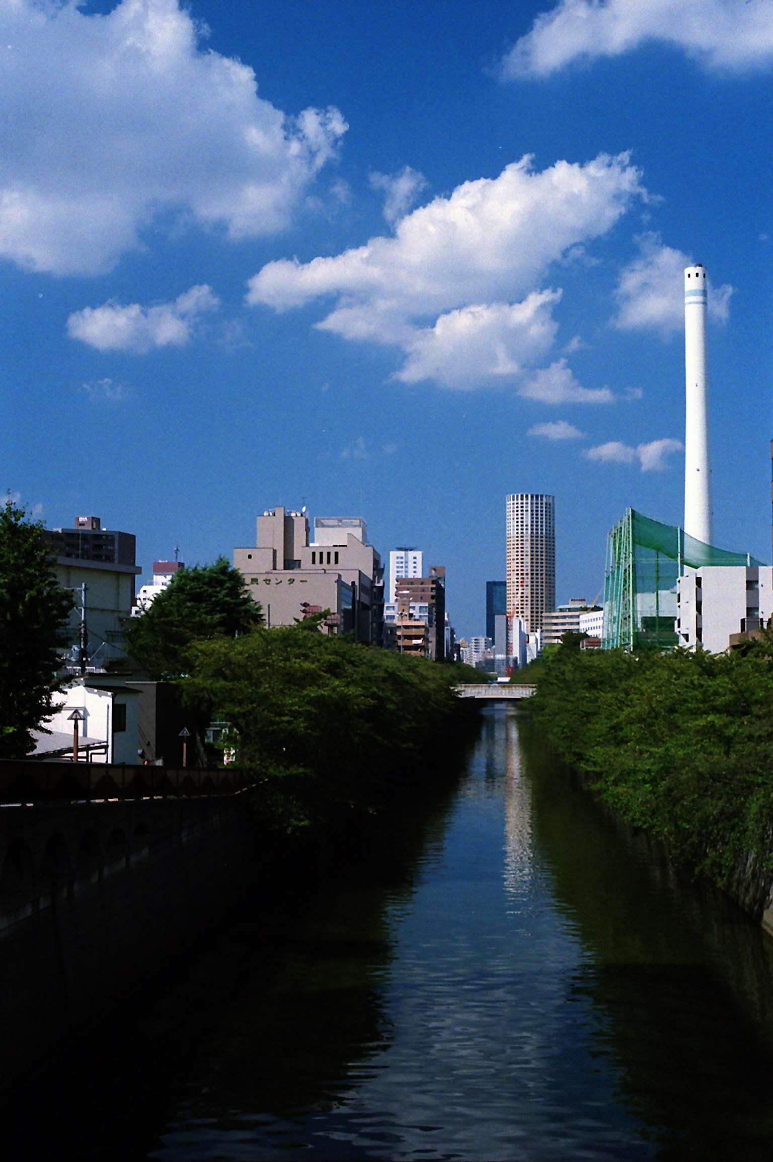 Paesaggio urbano lungo un fiume con cielo blu e nuvole