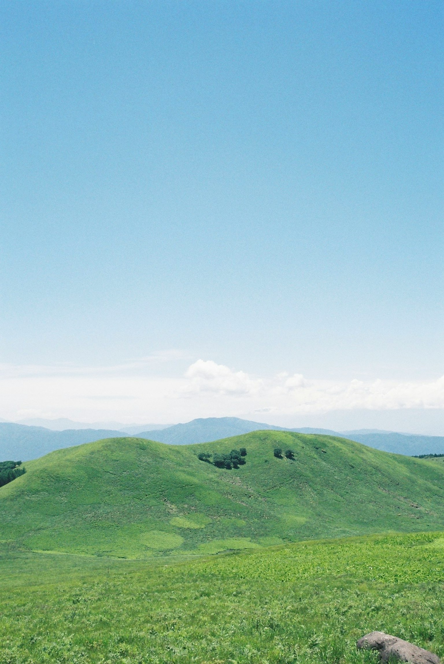 Pemandangan dengan bukit hijau di bawah langit biru jernih