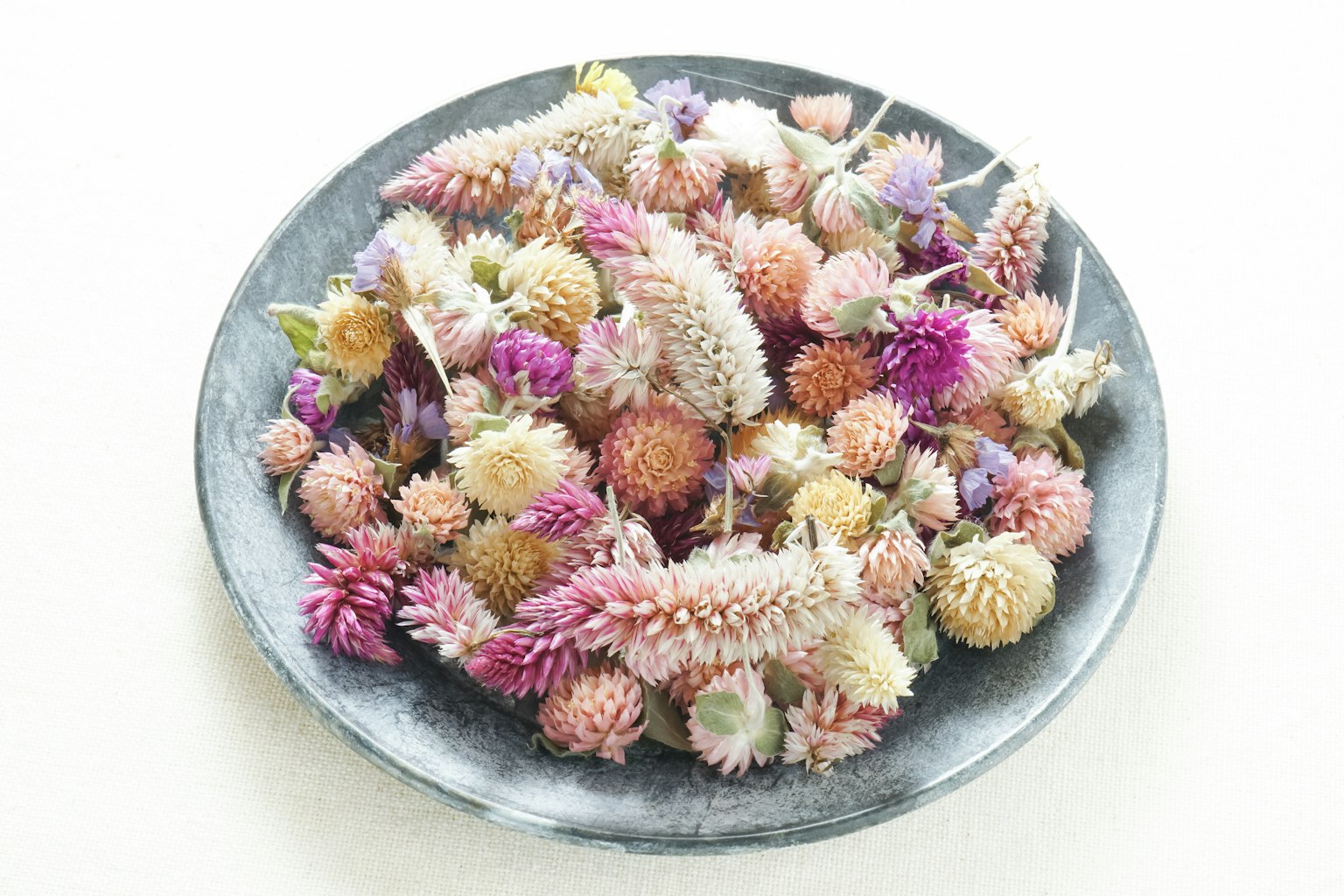 Fleurs séchées colorées disposées dans une assiette noire