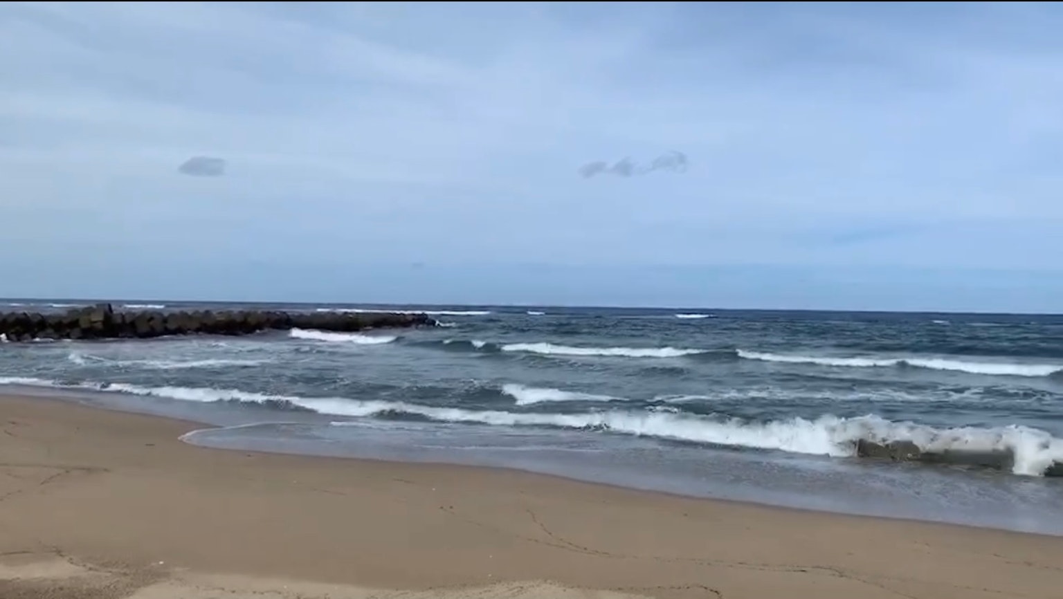 Calm waves hitting the beach with a wide view of blue sky and sea