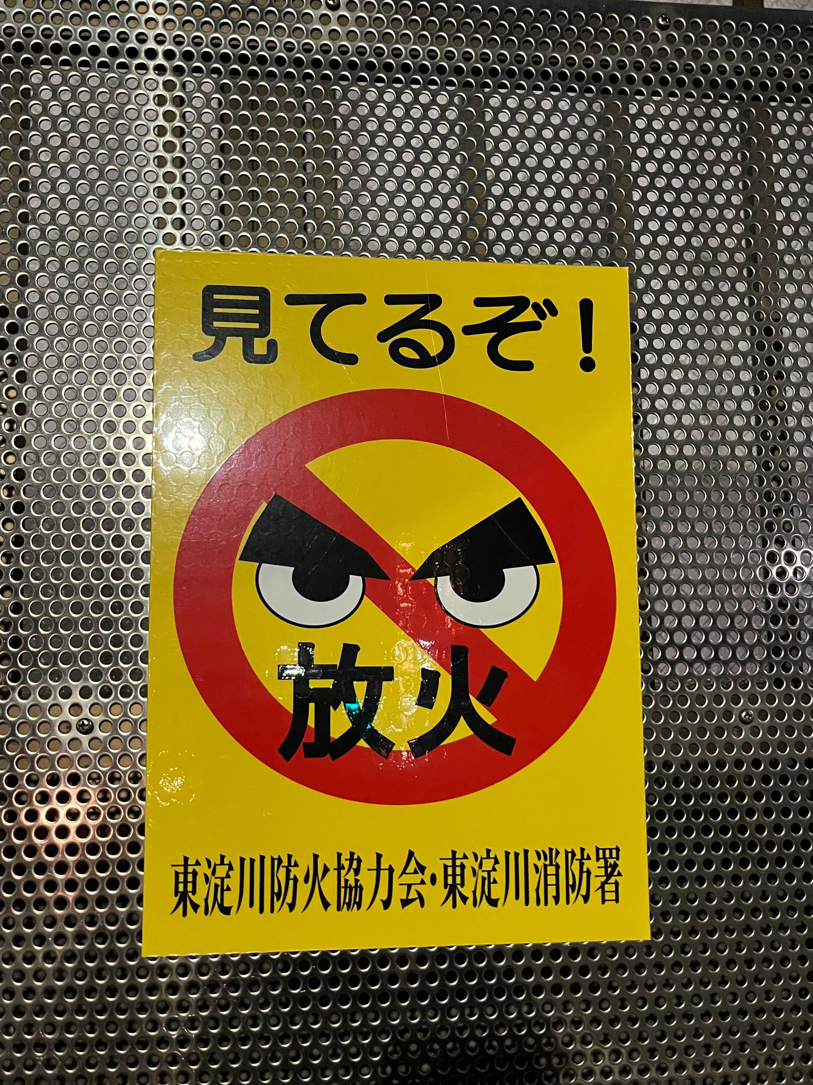 金属の壁に貼られた「放火」注意の掲示