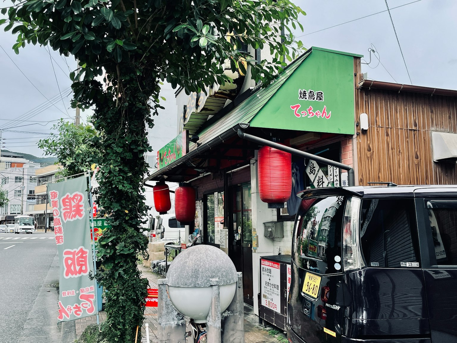작은 일본 식당의 외관 녹색 간판 빨간 등불과 검은 차