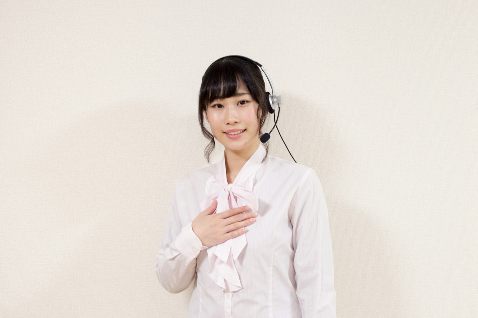 Une femme portant une chemise blanche et un casque, souriant et mettant la main sur sa poitrine