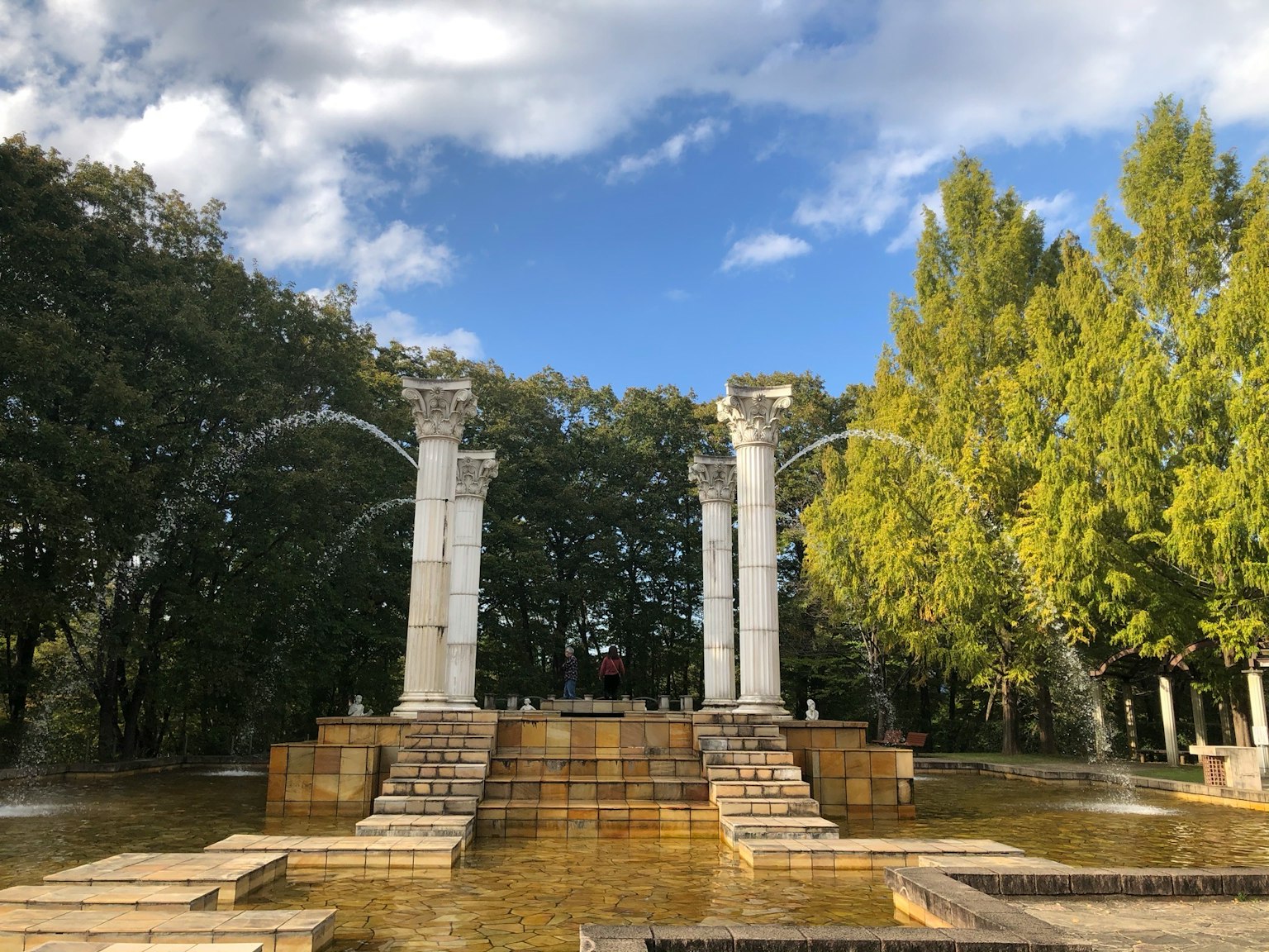 Landschaft mit Brunnen und klassischen Säulen in einem Park