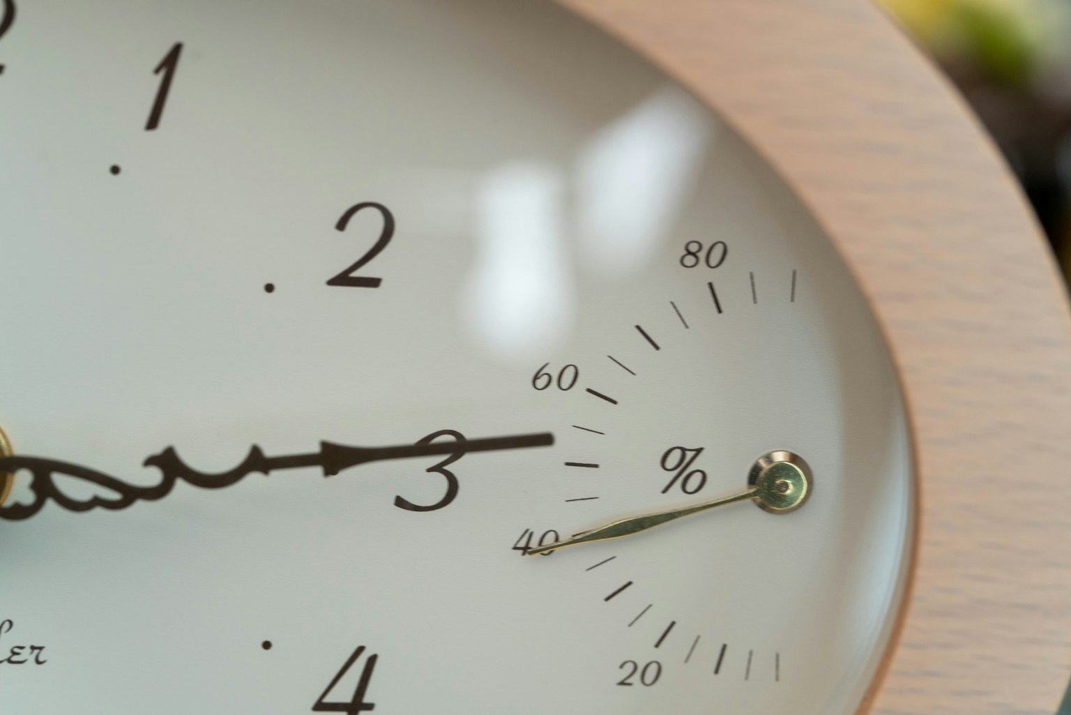 Nahaufnahme einer Holz-Uhr, die die Uhrzeit und ein Hygrometer anzeigt