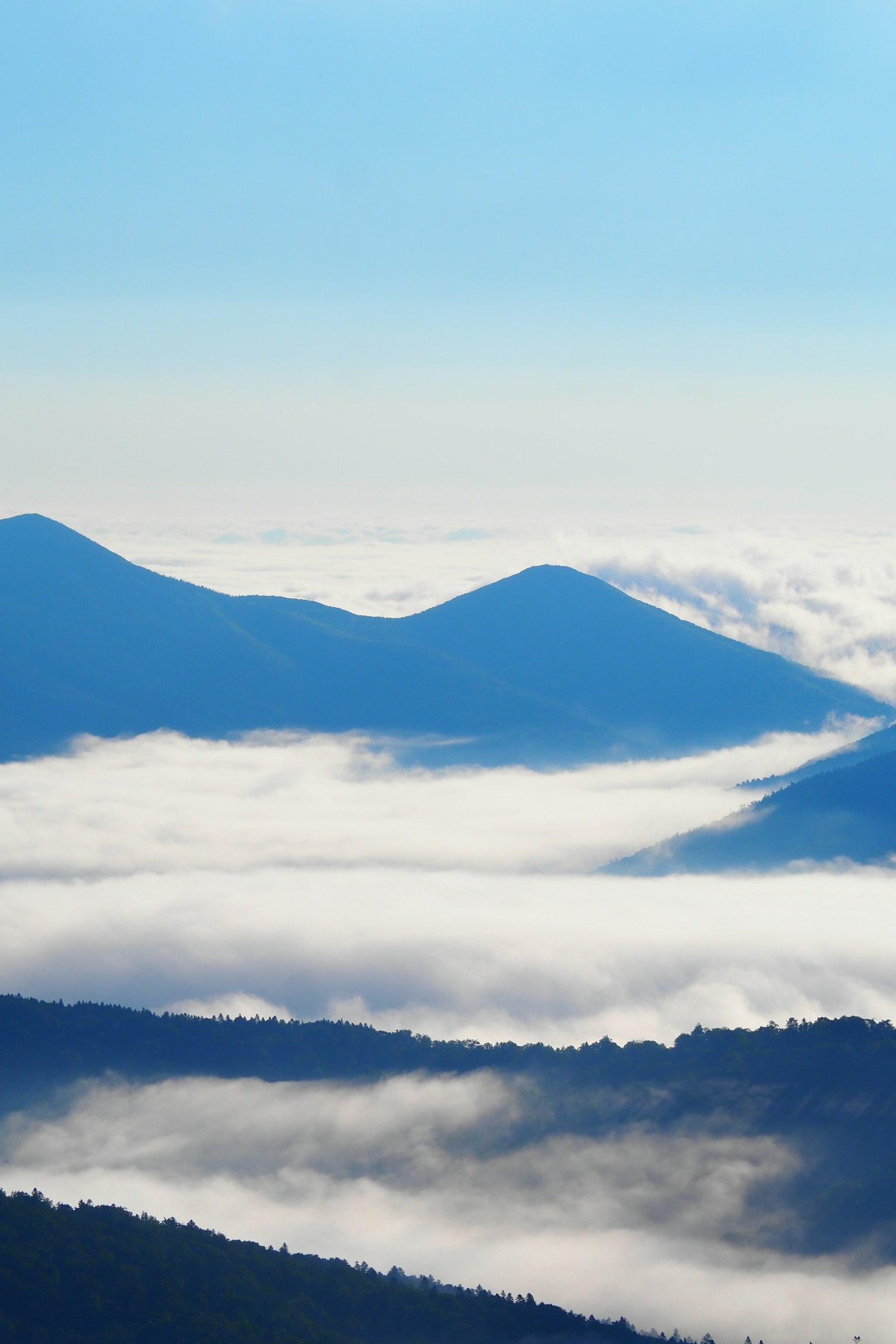 Vista panoramica di montagne coperte di nuvole sotto un cielo blu