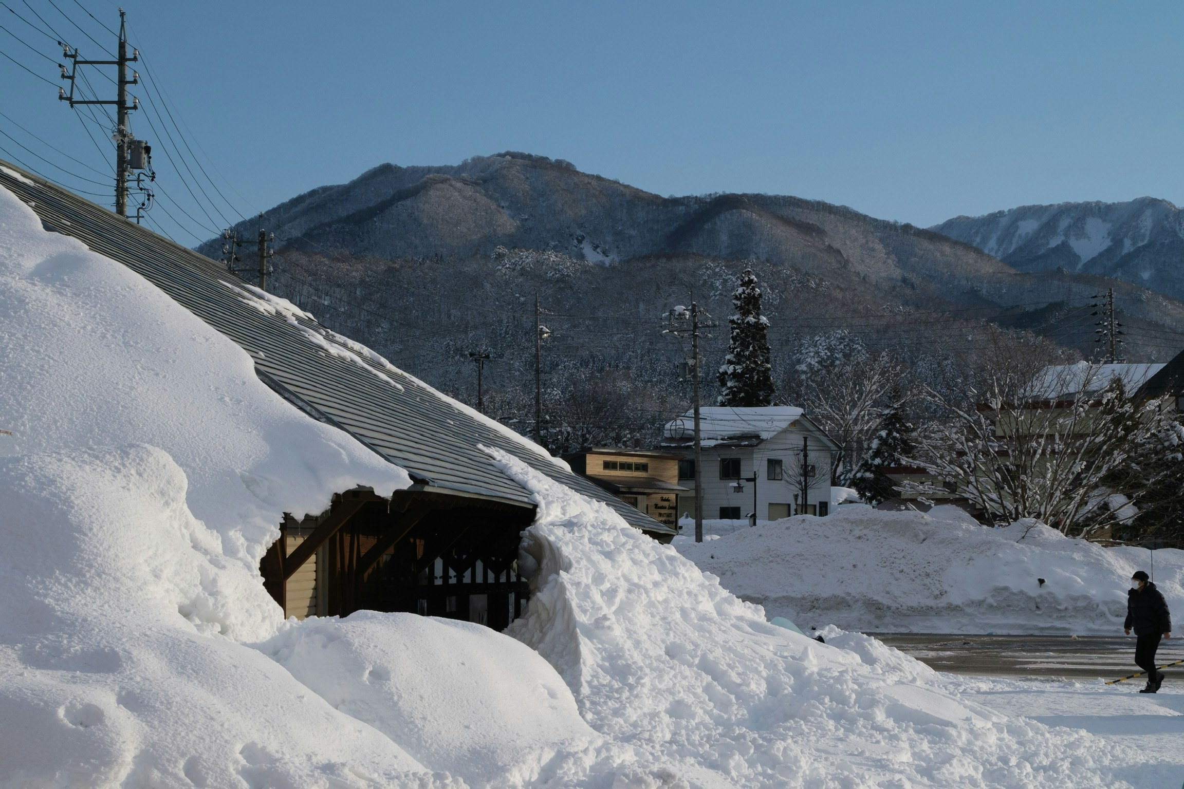 雪に覆われた山あいの集落と雪景色の道