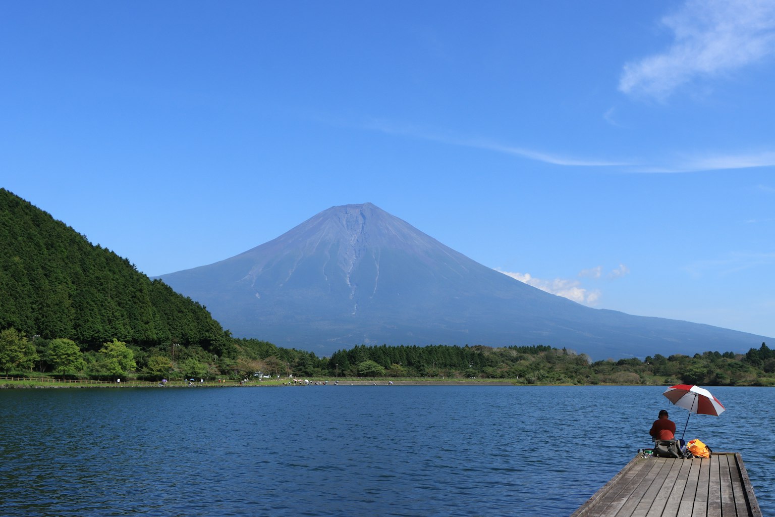 Pemandangan indah Gunung Fuji dengan danau dan orang-orang duduk di dermaga kayu