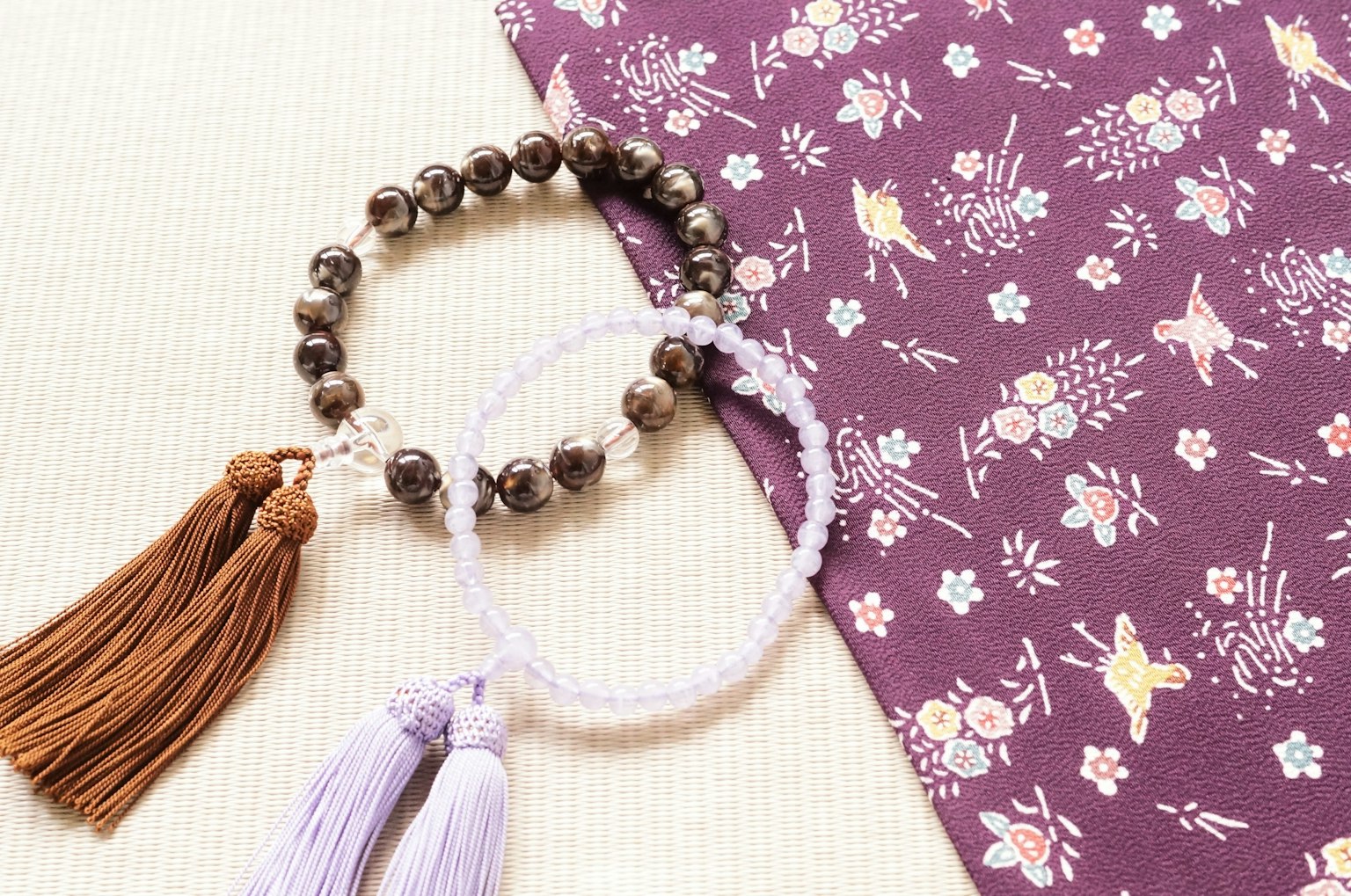 สร้อยข้อมือสองเส้นพร้อมพู่บนผ้าลายดอกไม้สีม่วง