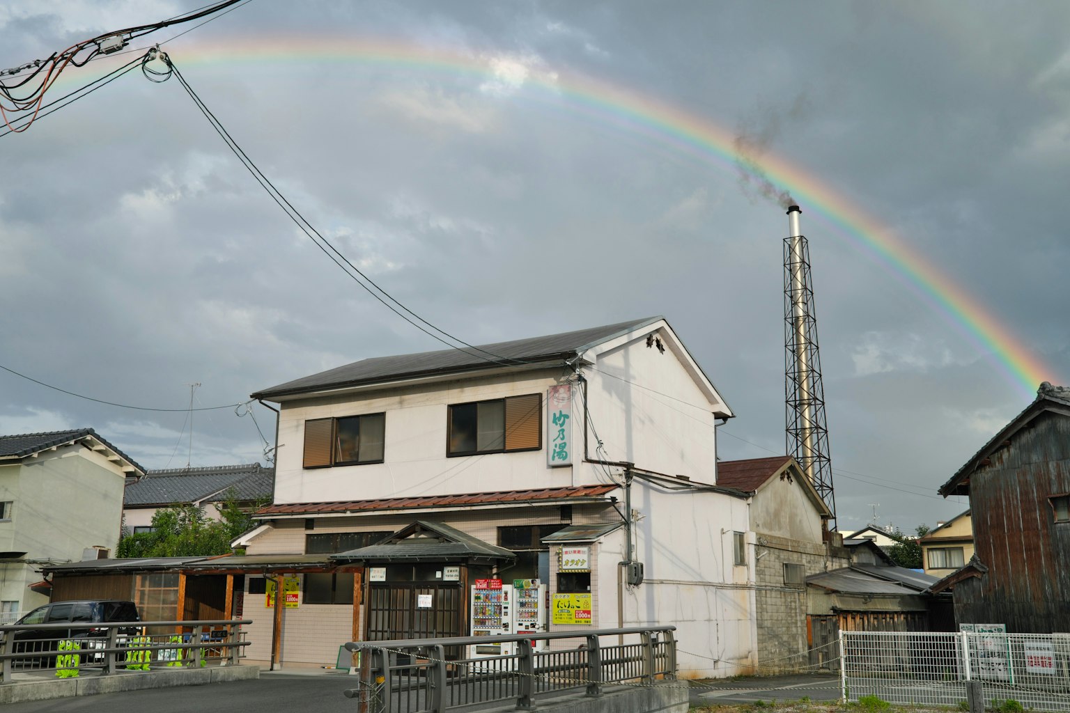 Ein weißes Haus unter einem Regenbogen mit umliegenden Gebäuden