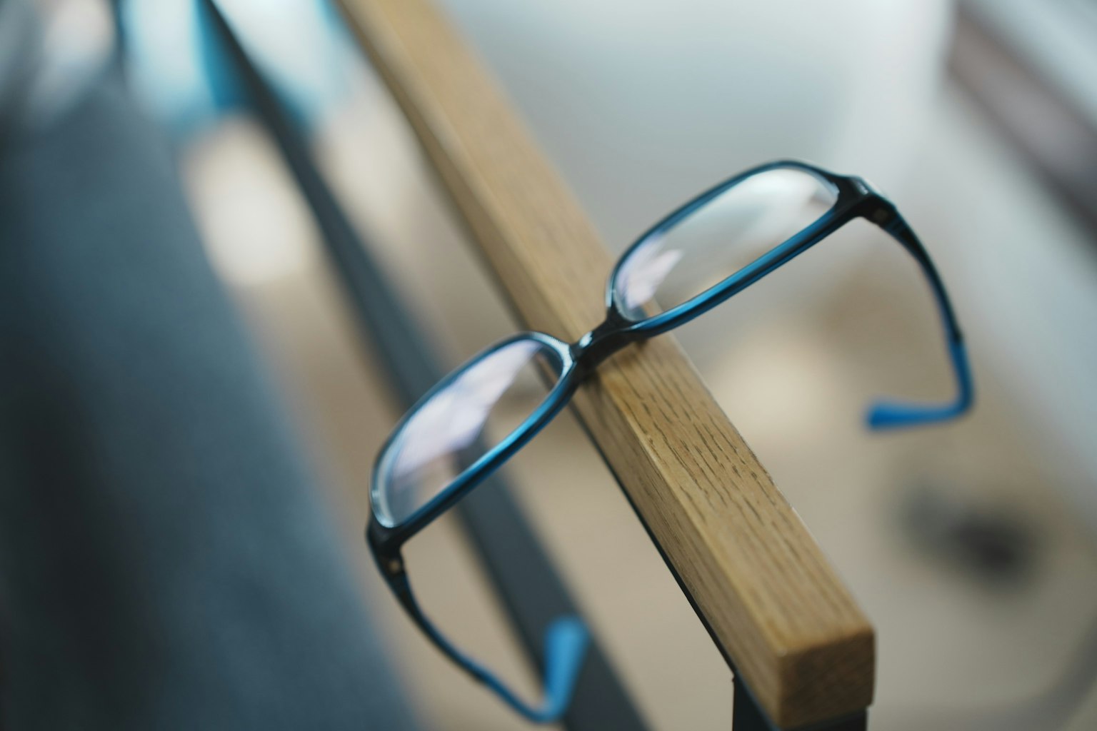 Gafas con montura azul apoyadas en una barandilla de madera