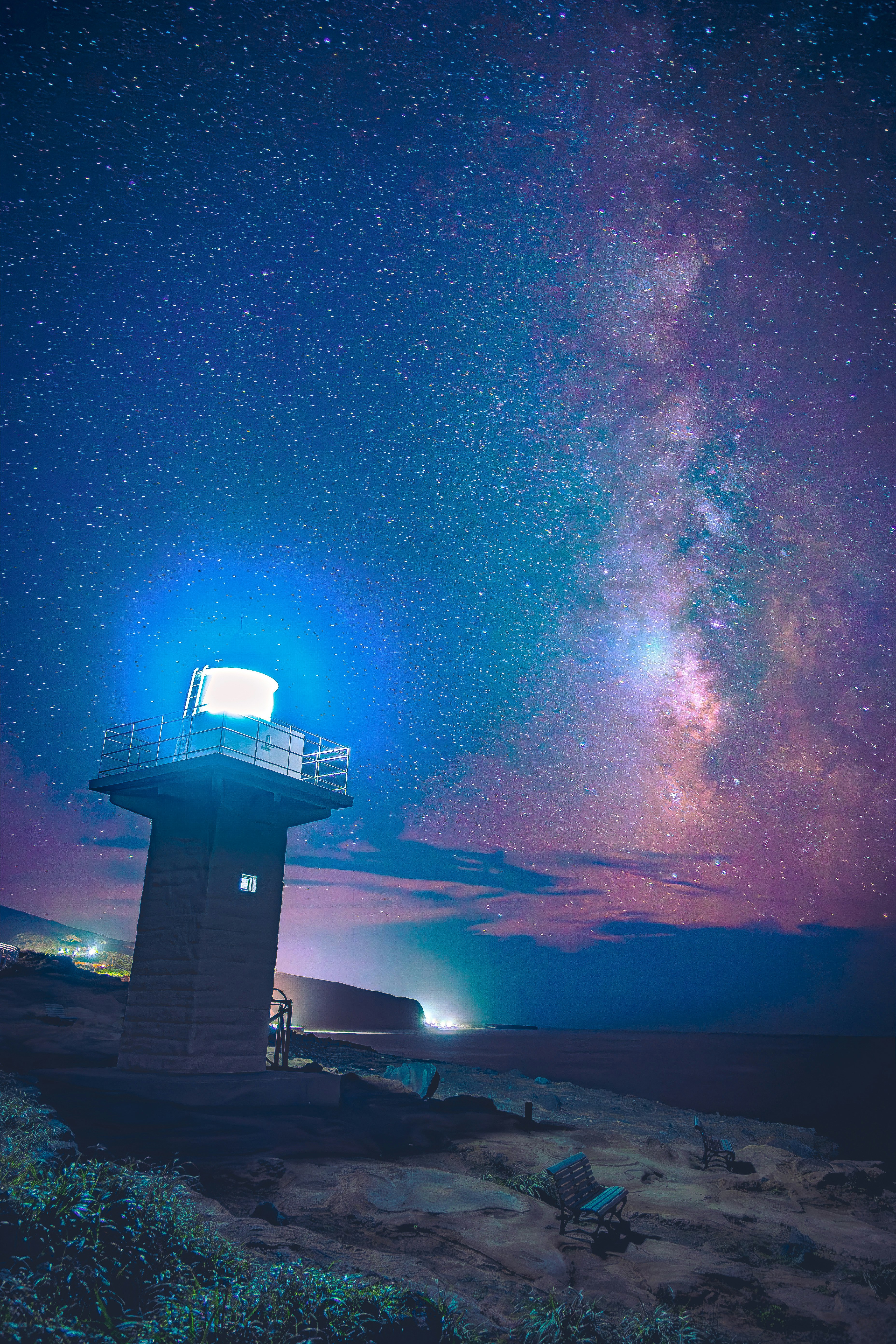 灯台と満天の星空、天の川が広がる海辺の夜景