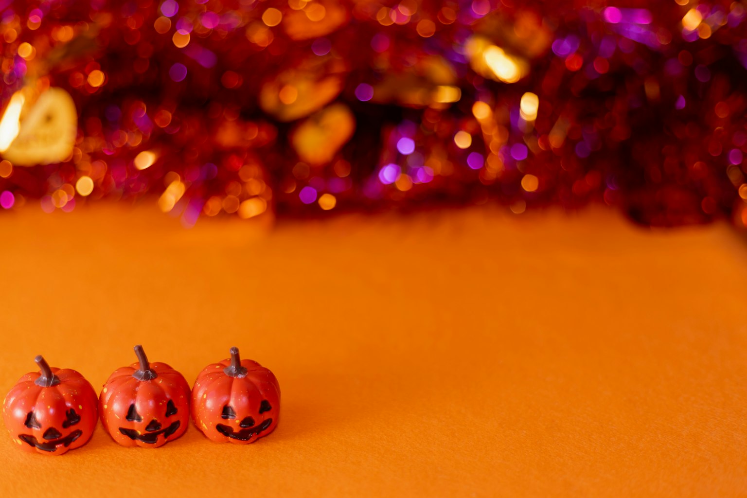Pequeñas decoraciones de calabaza con cara en un fondo naranja