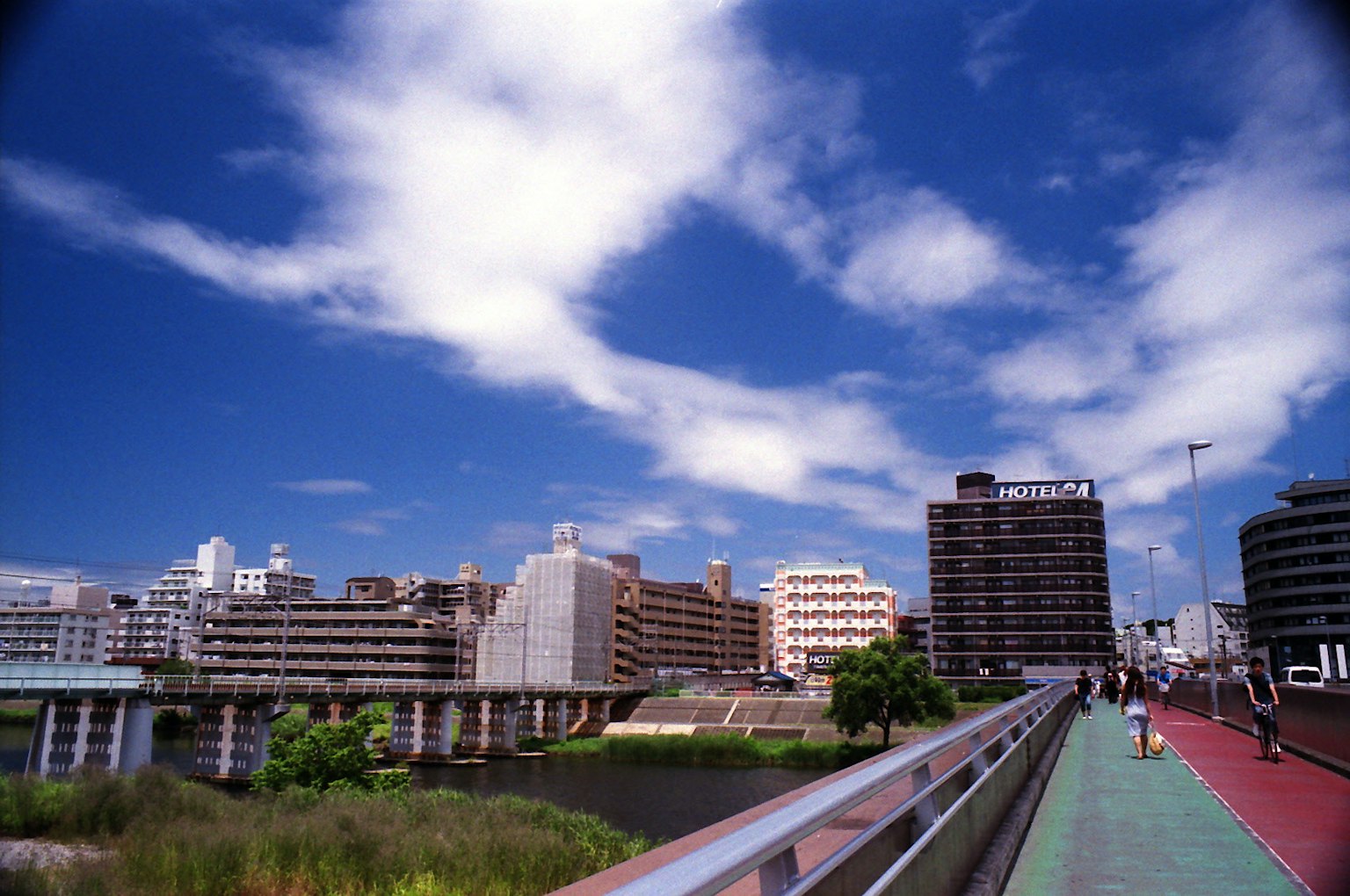 Paesaggio urbano con cielo blu e nuvole, passeggiata lungo il fiume e edifici