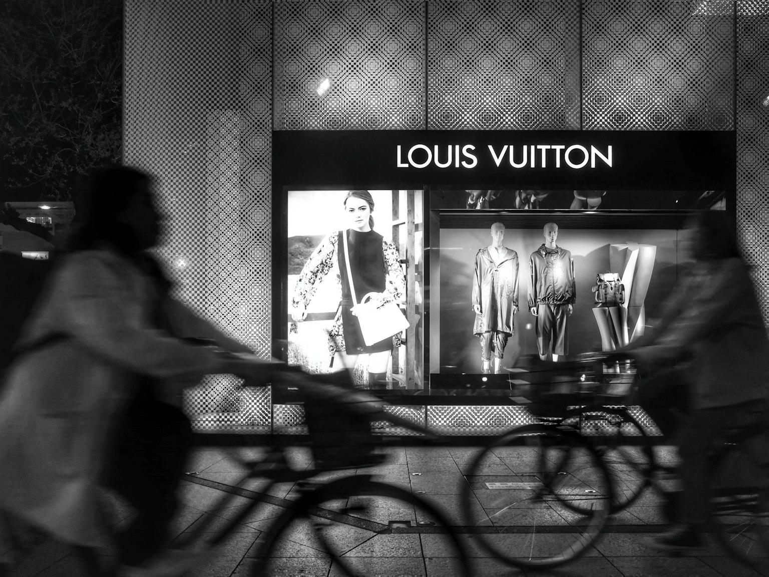 Scena di strada con ciclisti davanti alla vetrina di Louis Vuitton