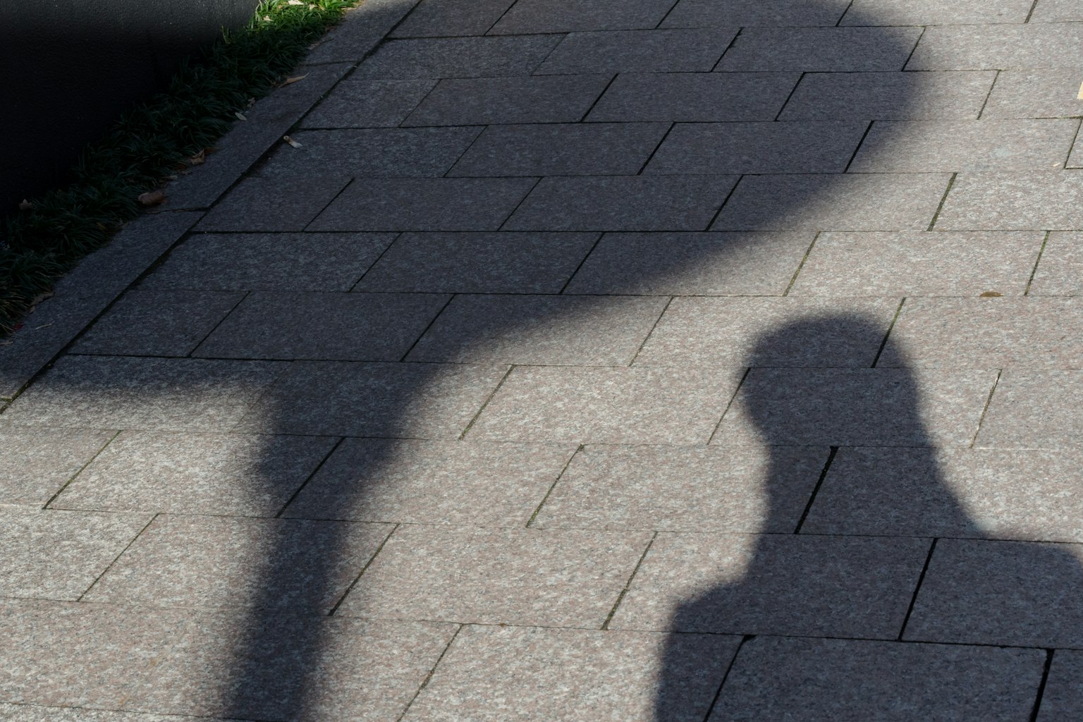 Ombre d'une personne et d'un panneau de rue sur le pavé
