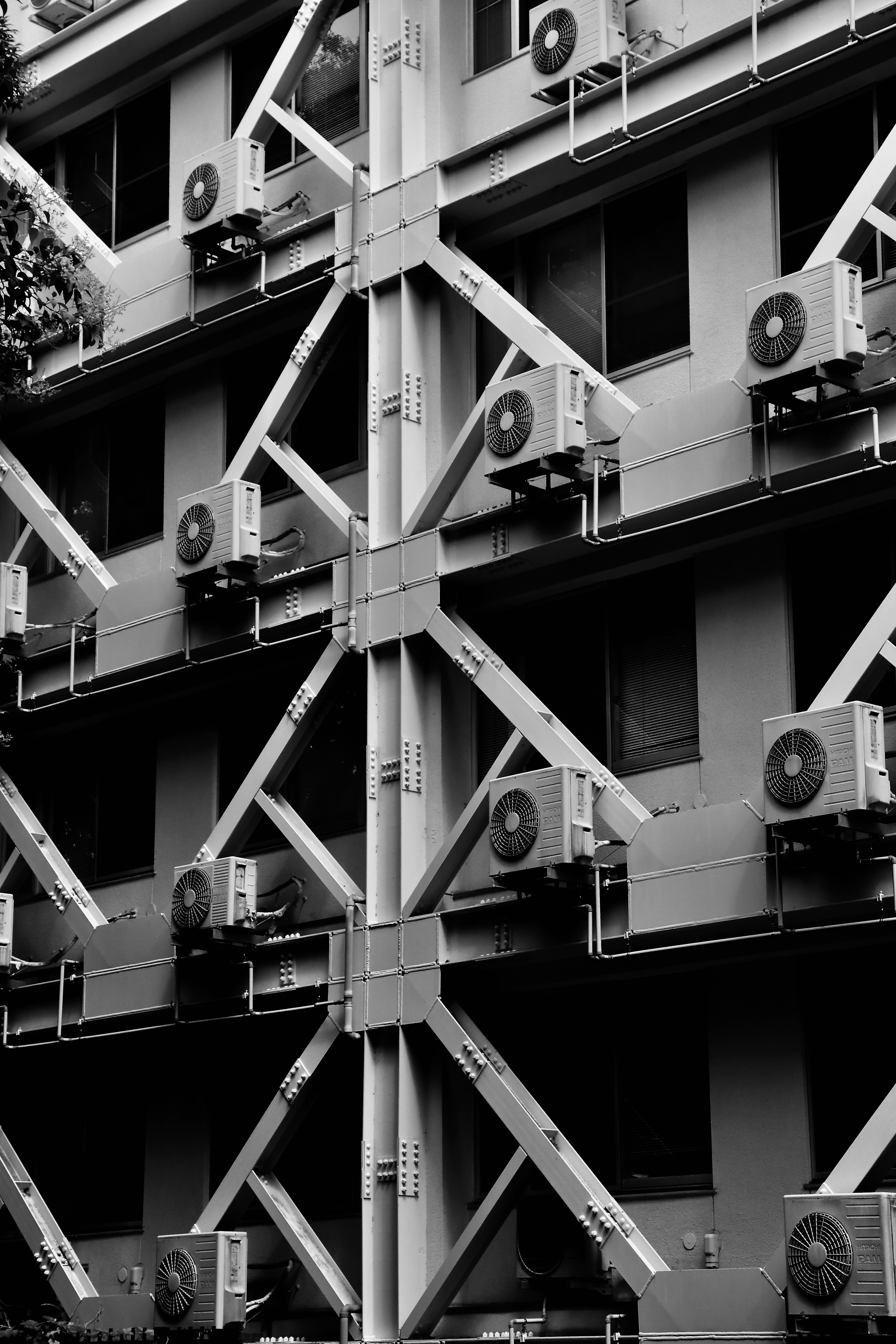 格子状の建物外壁に並ぶ換気扇のモノクロ画像