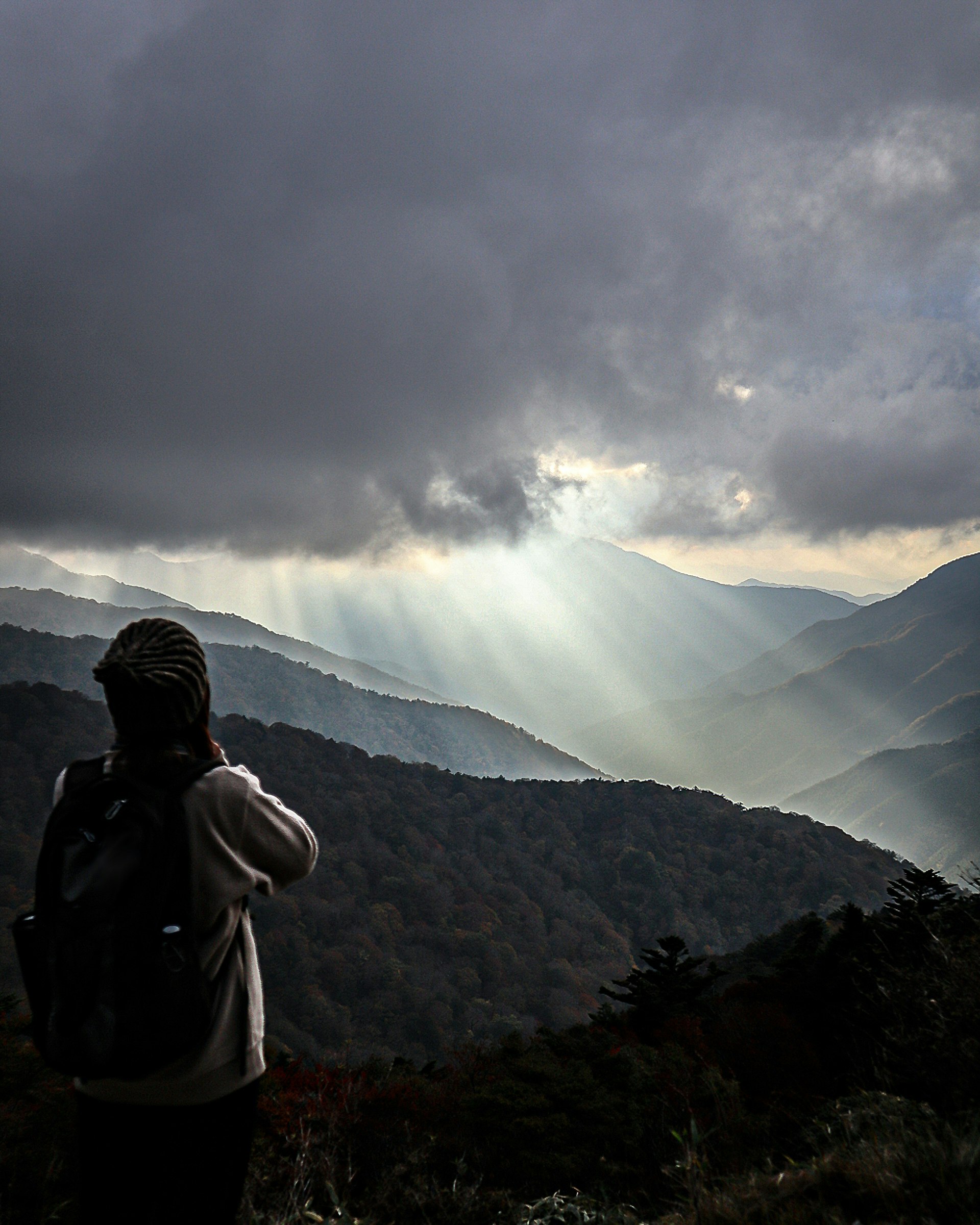 雲間から光が差す剣山の山稜と登山者のシルエット